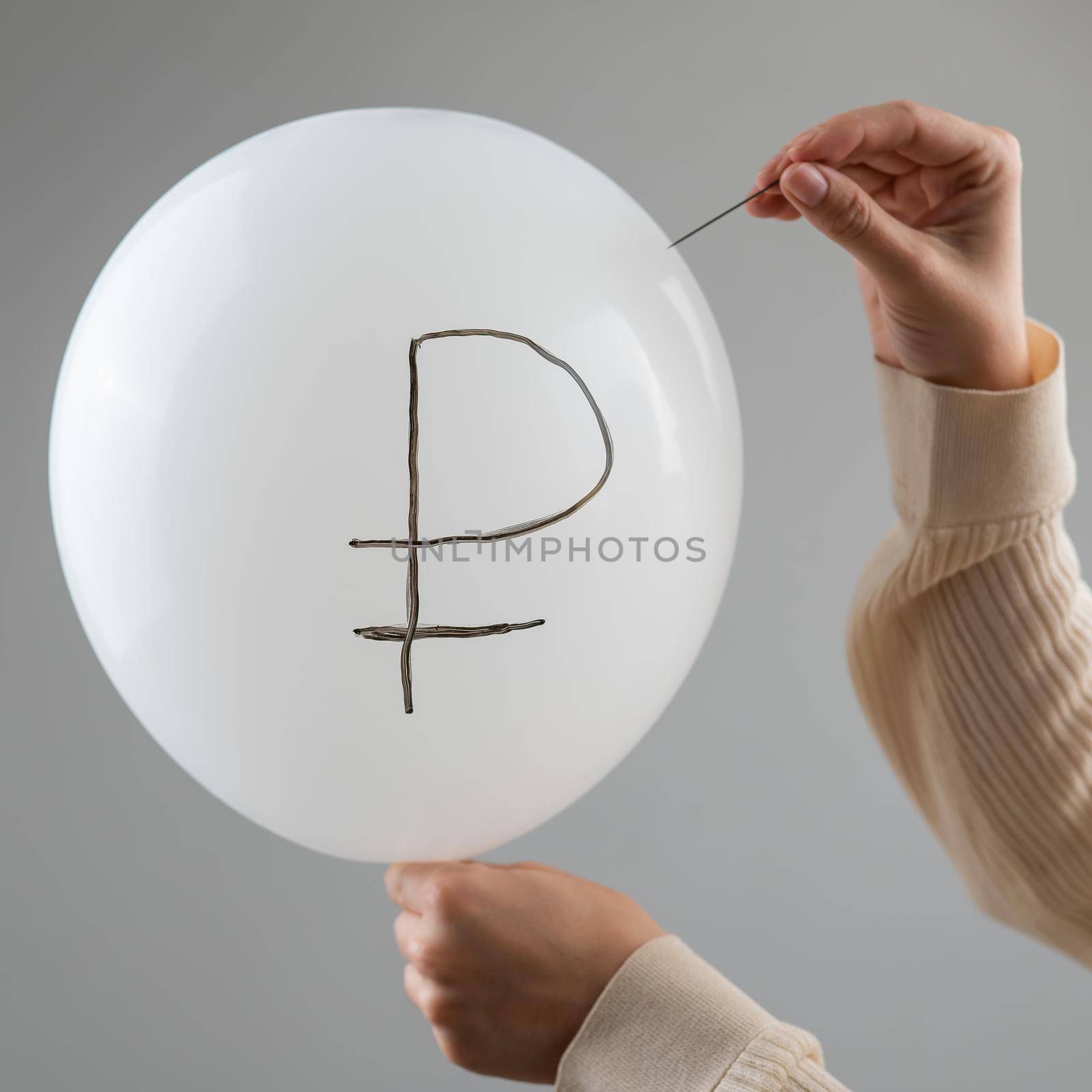 Caucasian woman pops a balloon with a ruble inscription with a needle. by mrwed54