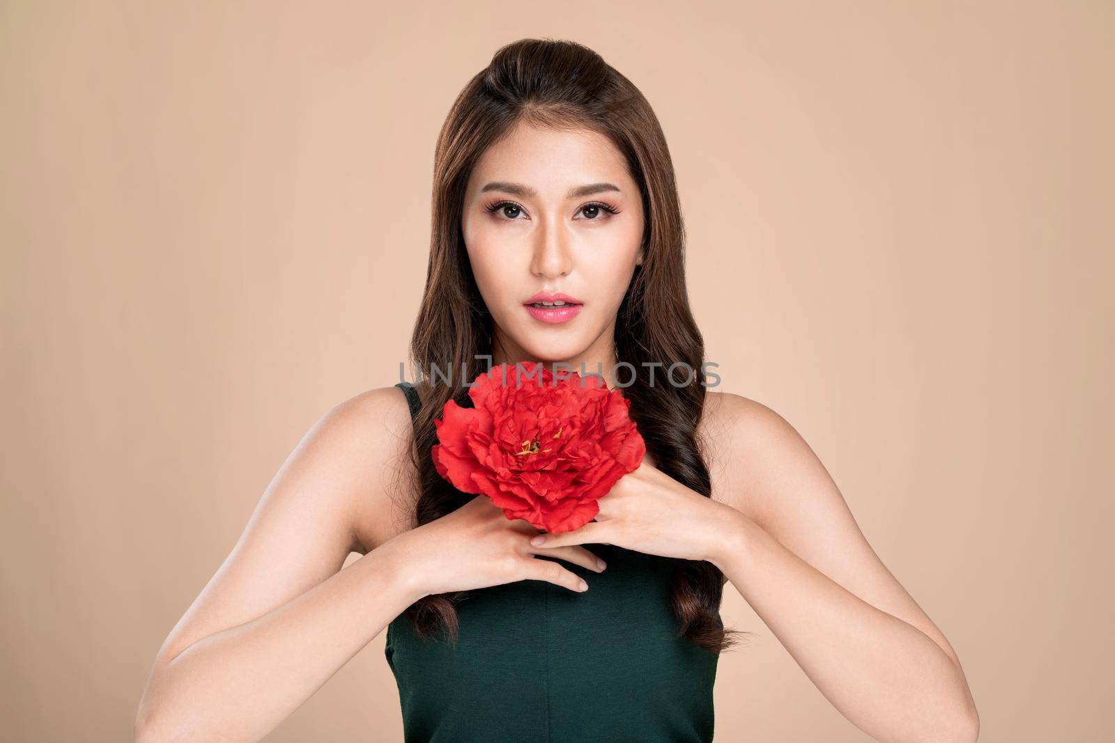 Ardent female model with flawless fair skin and perfect makeup holding flowers. Woman receive flowers, white background.
