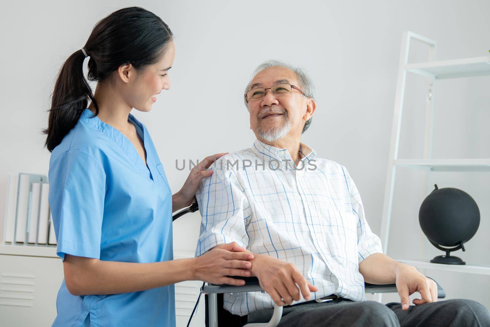 Happy positive asian nurse giving support and touching contented senior man. by biancoblue