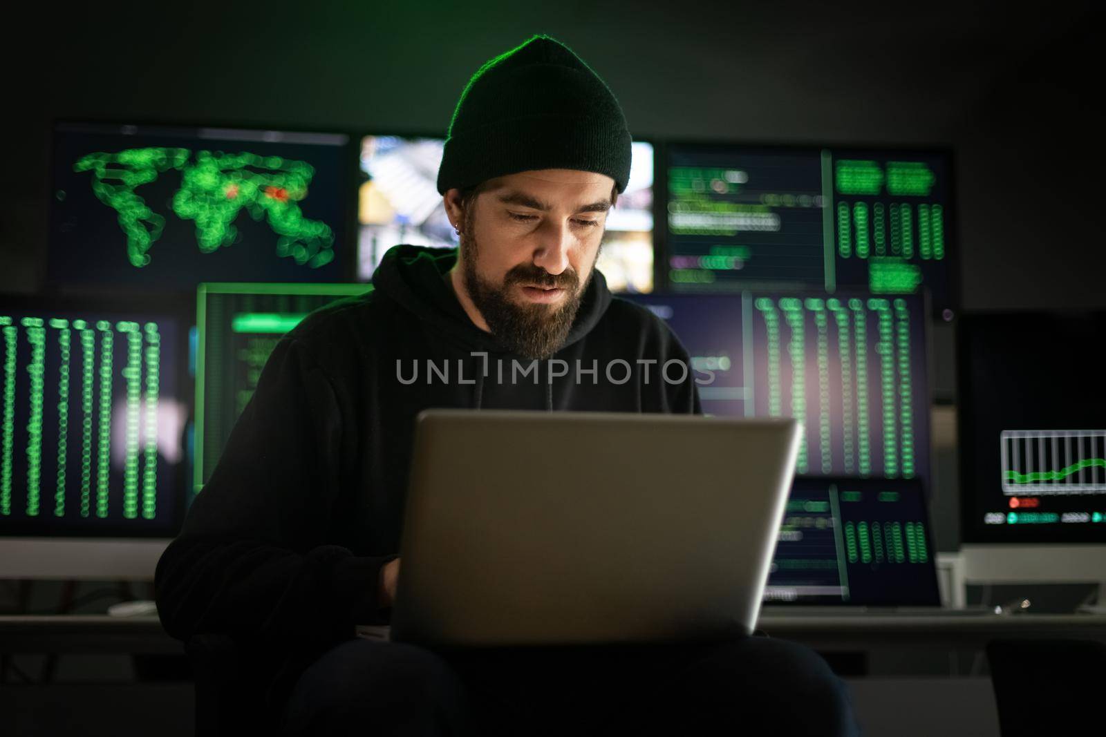 Caucasian male hacker using laptop to organize malware attack on global scale. Hacking concept.