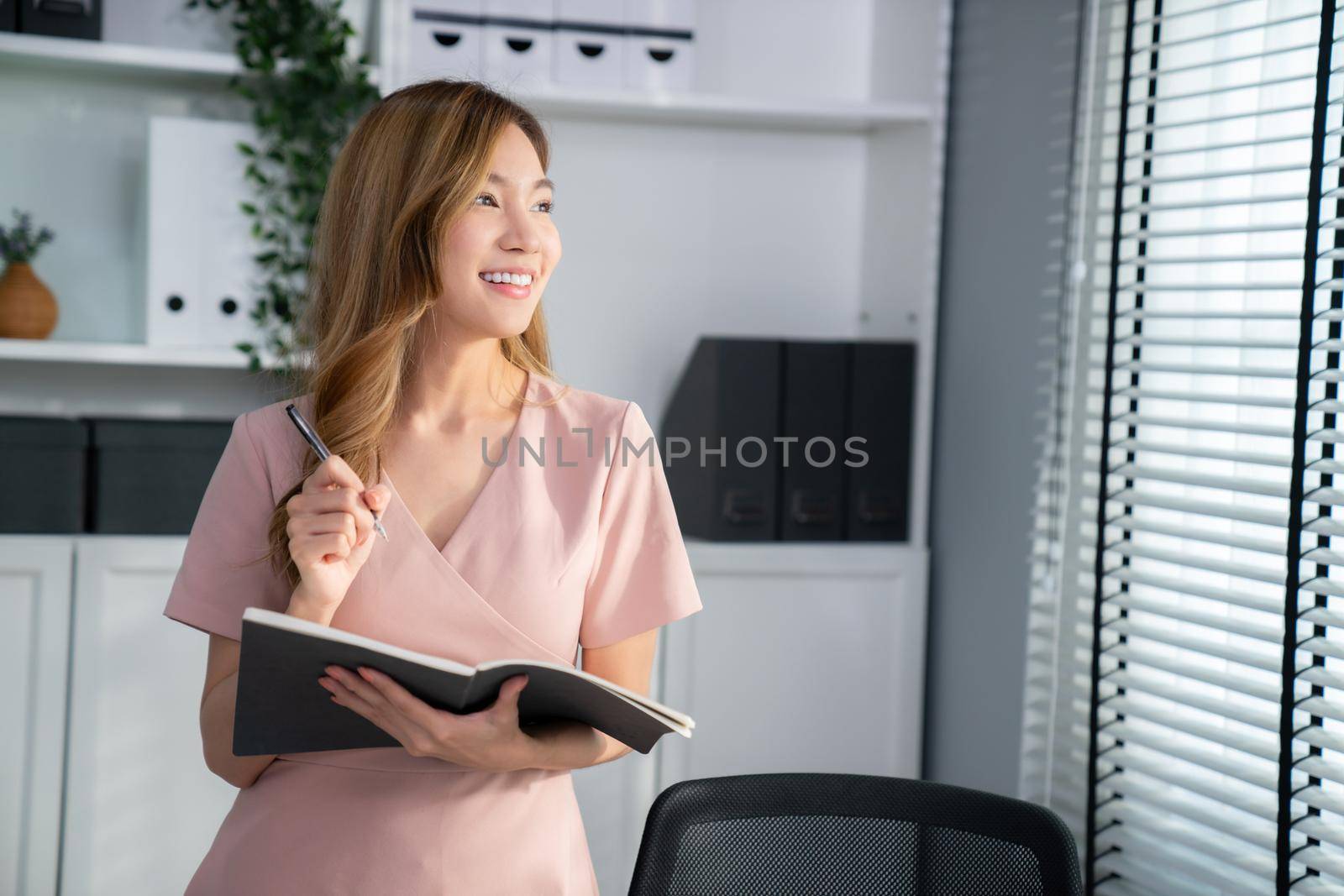 Young competent office lady, intern, secretary holding a log in office room. Concept of various career for office working. Concept of diverse office careers.