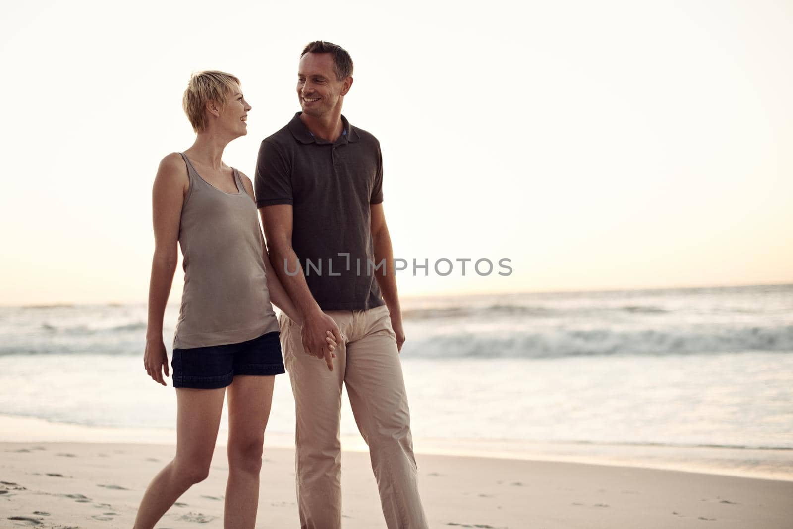 I love long walks on the beach. a mature couple taking a walk on the beach. by YuriArcurs