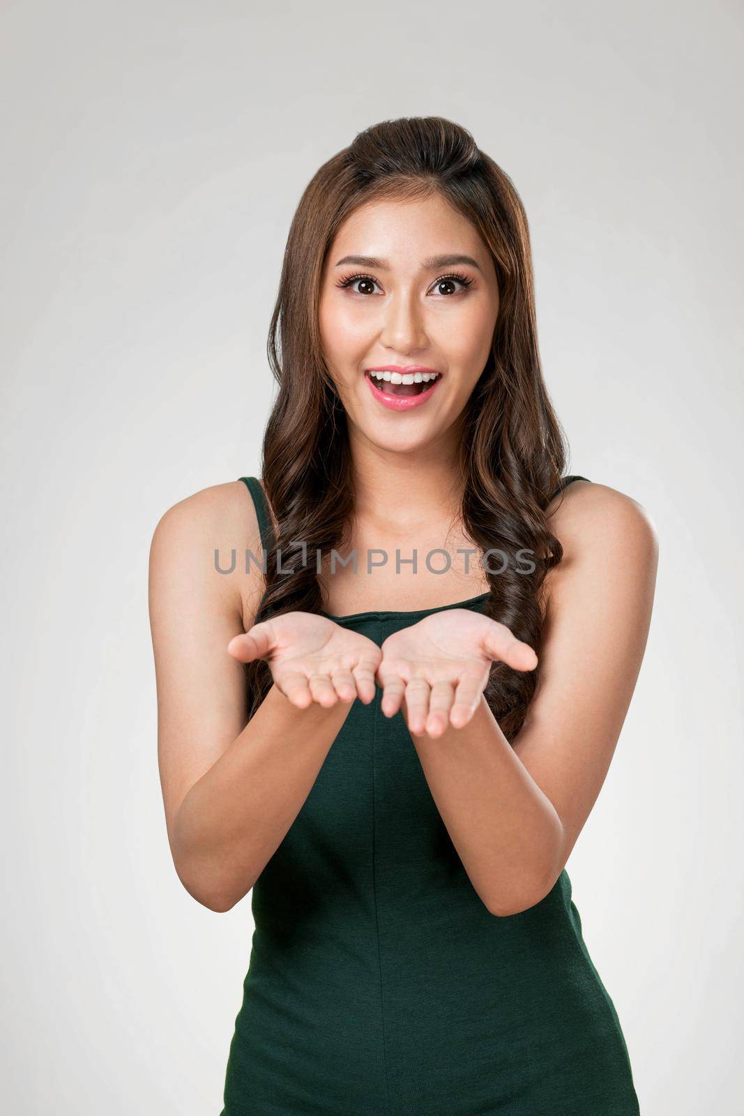 Portrait of ardent woman looking at camera, holding empty space for product, advertising text place, isolated background. Concept of healthcare advertising for skincare, beauty care product.