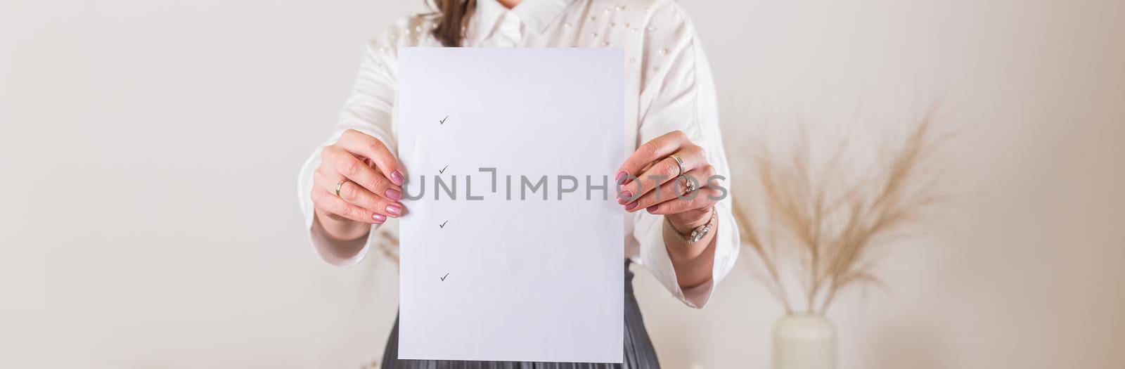 Woman holding clipboard with a blank sheet of paper. Blank paper poster in female hands.