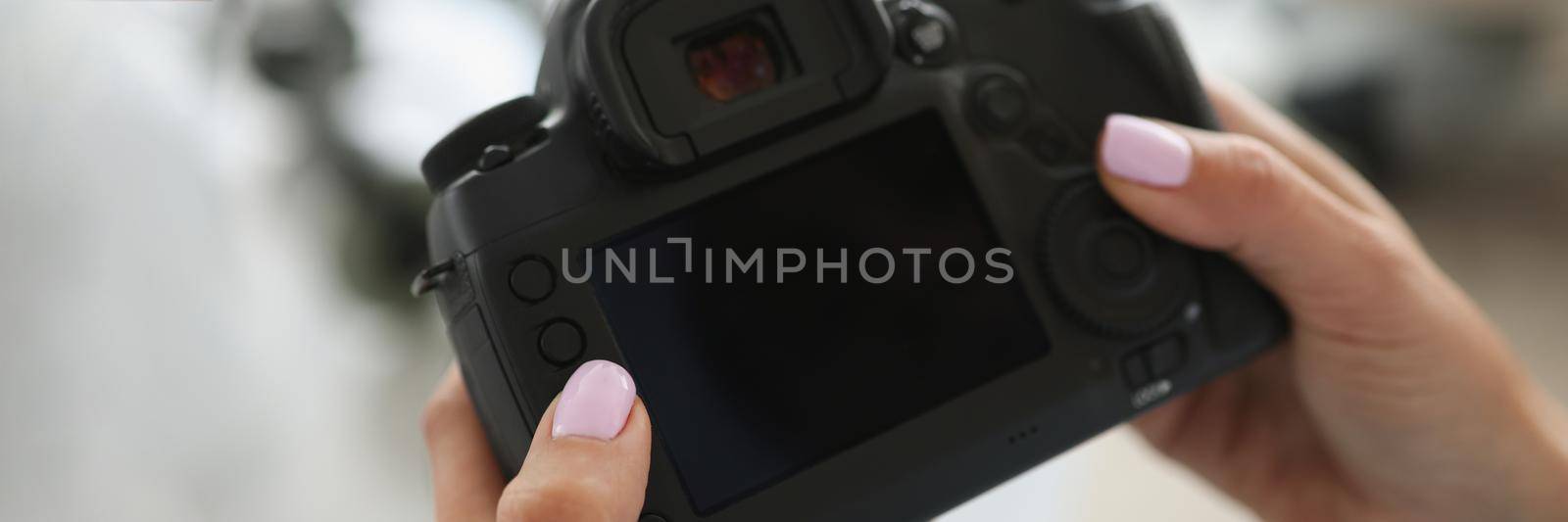 Female hands are holding a black modern camera by kuprevich