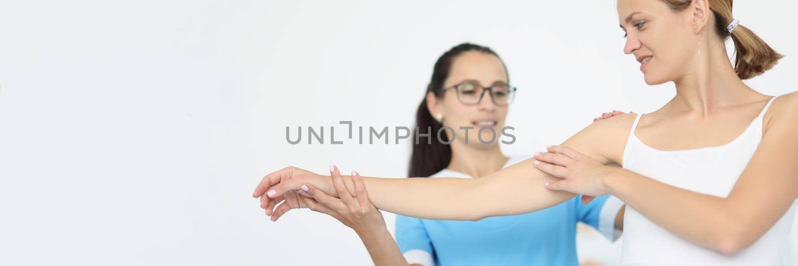 The doctor holds the hand and shoulder of a sick woman, close-up. Rehabilitation, muscle recovery, arm pain