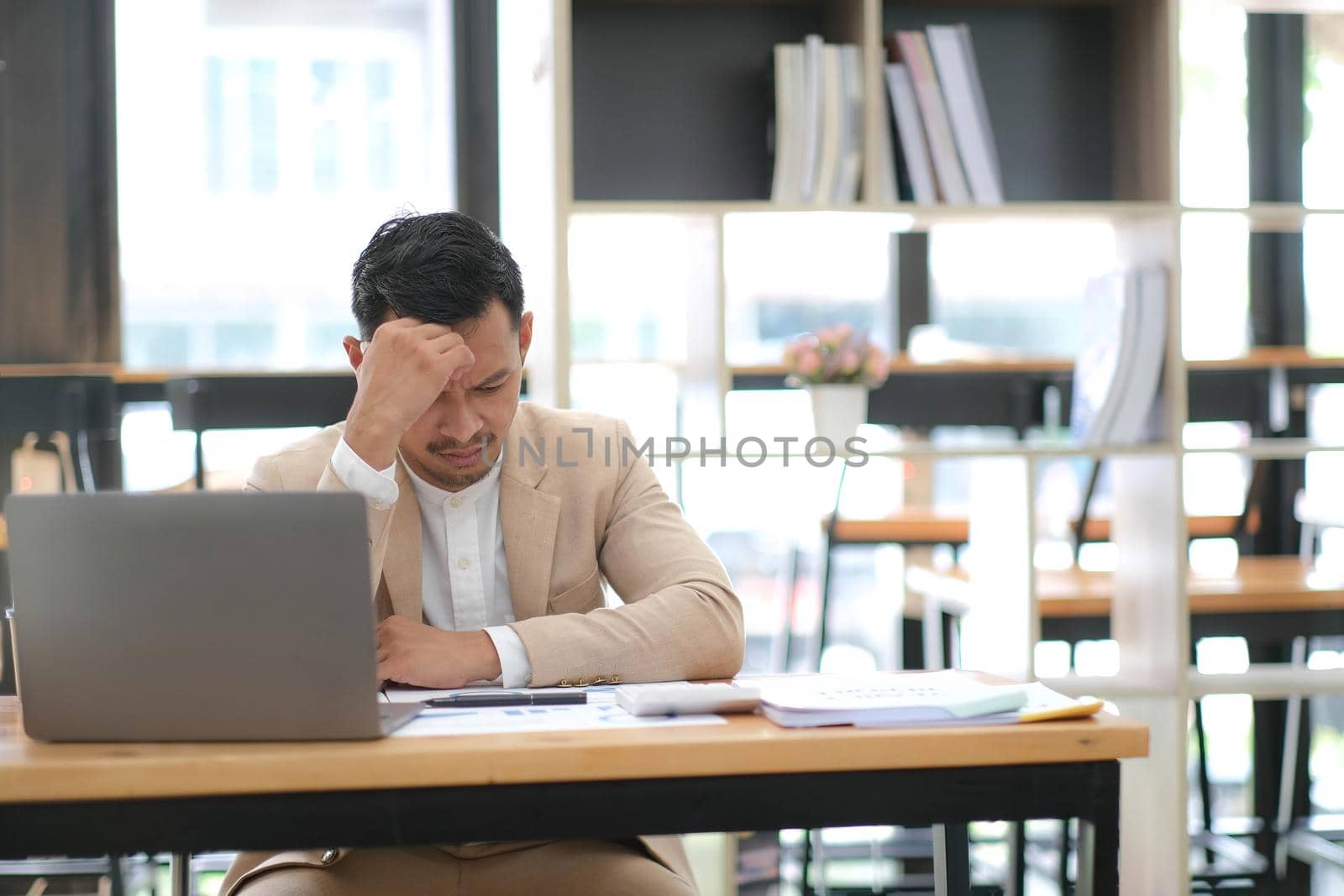 Tired frustrated young asian businessman feeling stressed holding head with hands, business problem failure concept by wichayada