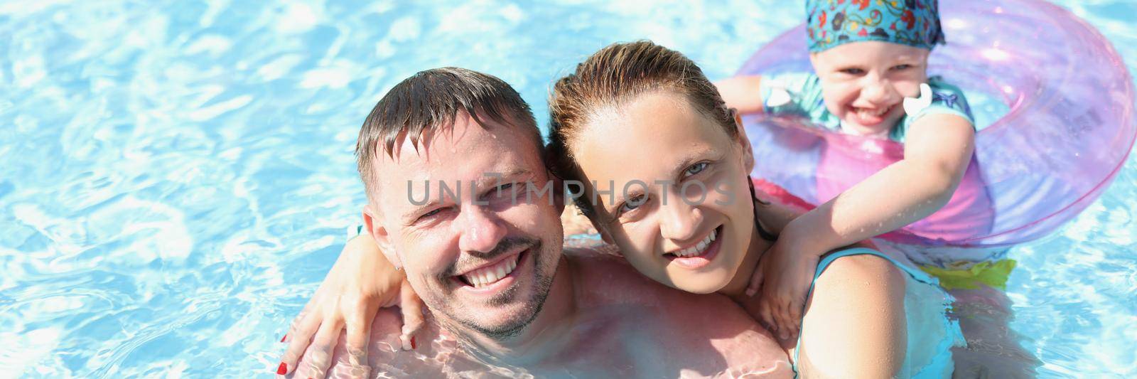 Husband with wife and child swim together in the pool by kuprevich