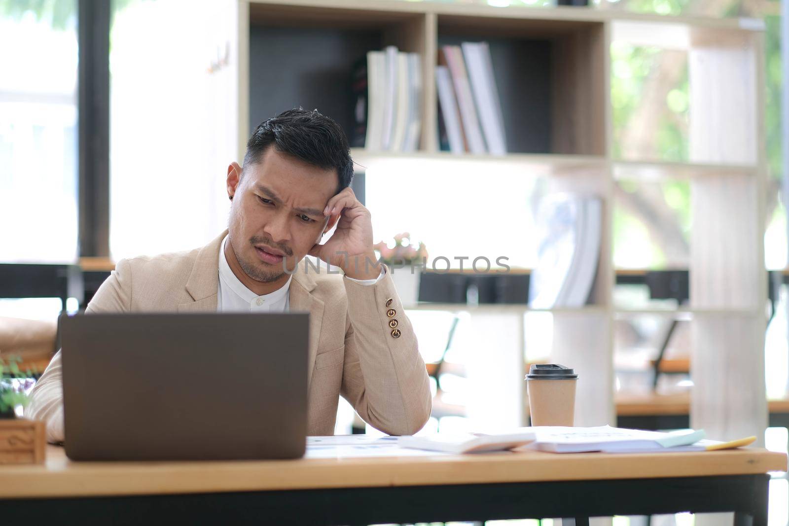 Tired frustrated young asian businessman feeling stressed holding head with hands, business problem failure concept.