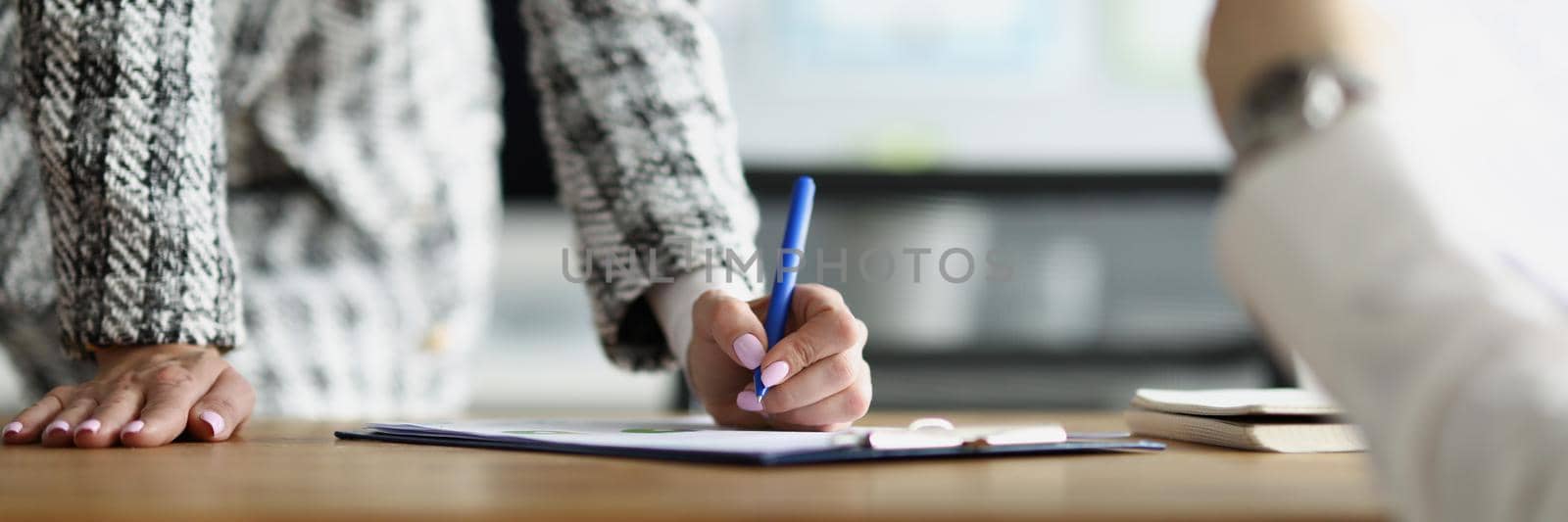 A woman in the office in the presence of a man signs documents, close-up, blurry. Dismissal of an employee