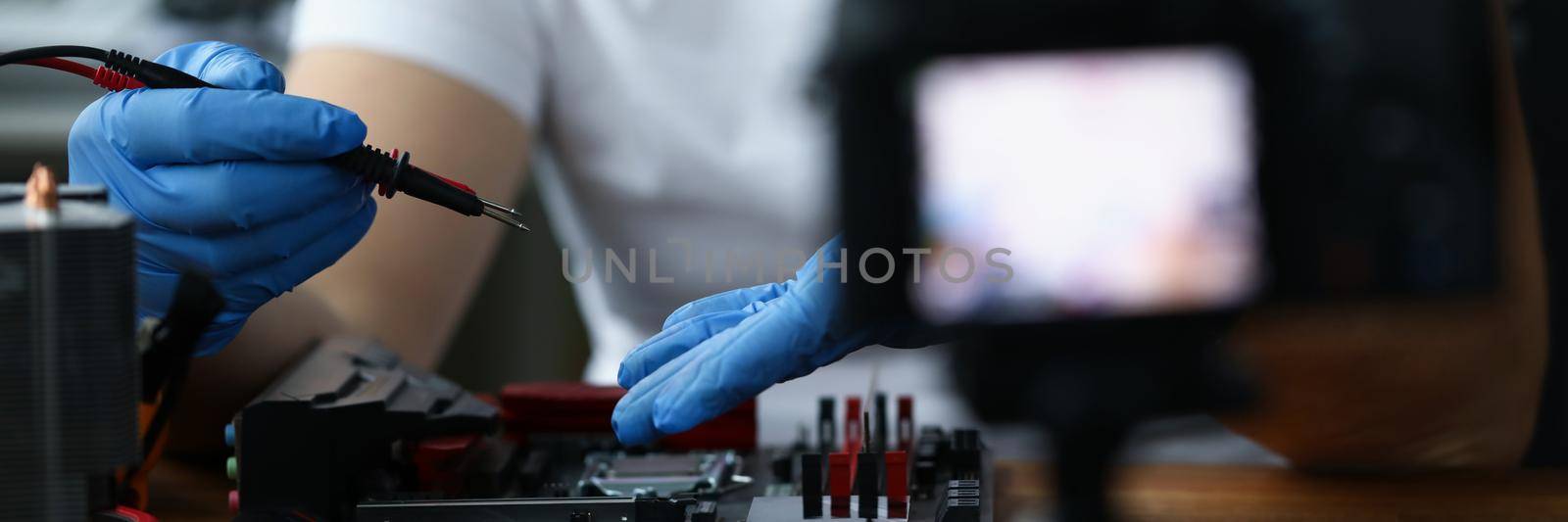 A man makes a video blog on repairing a pc, close-up, blurry. The camera is filming the repair of a digital device