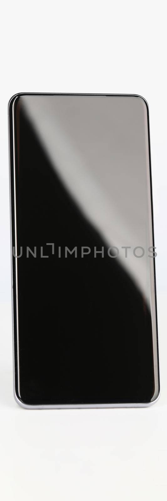 Black smartphone stands upright on a white background, close-up. New device sale, blank screen, digital app, touchscreen