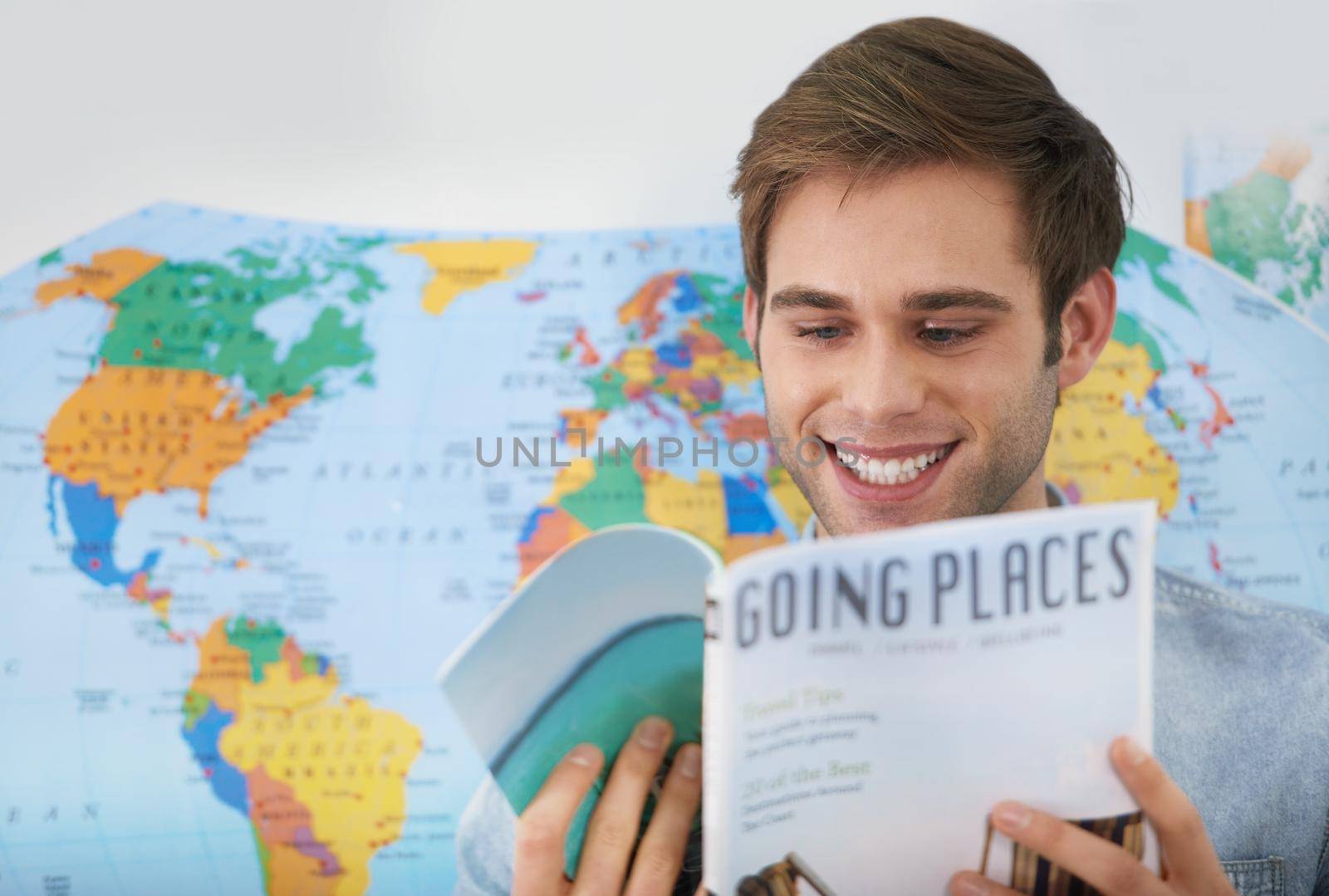 Dreaming about traveling. A young man reading a travel magazine