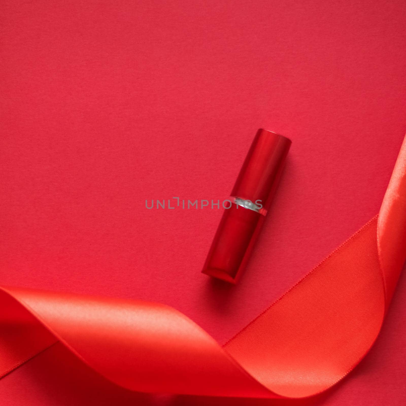 Cosmetic branding, glamour lip gloss and shopping sale concept - Luxury lipstick and silk ribbon on red holiday background, make-up and cosmetics flatlay for beauty brand product design