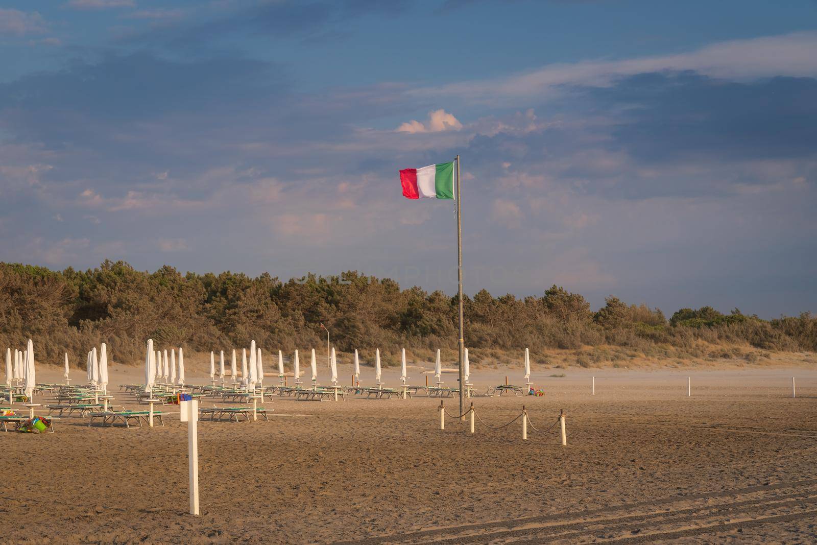 Italian flag waving in the wind on the beach at sunrise