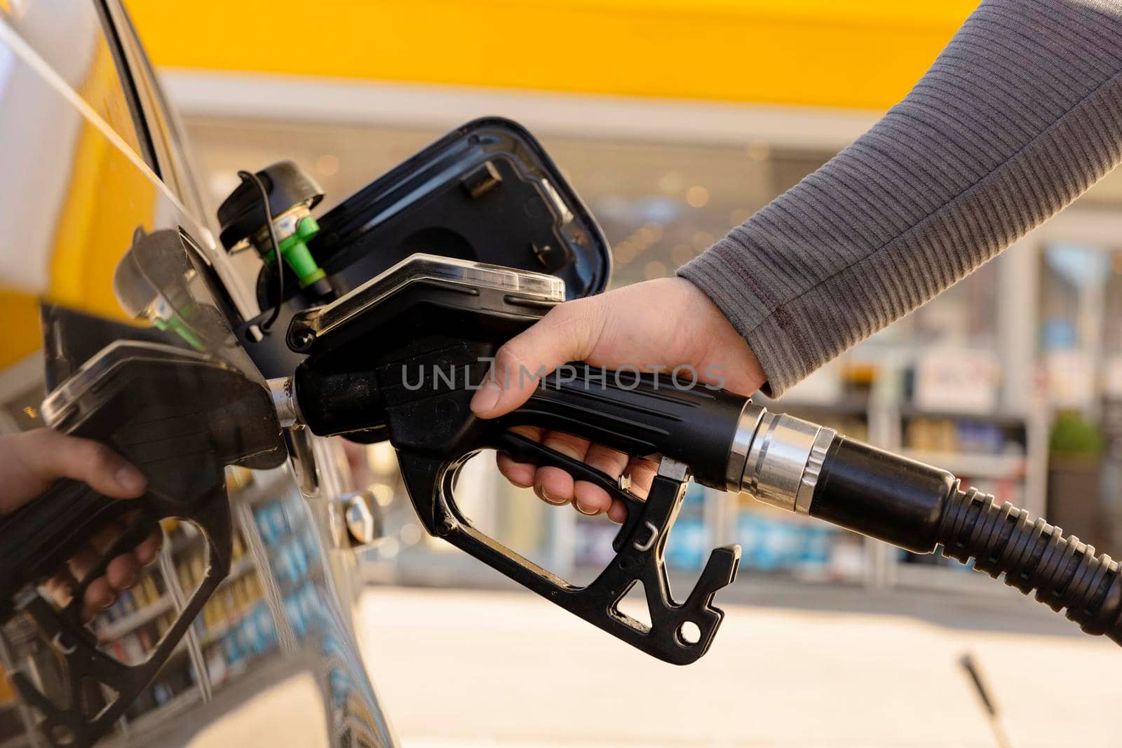 Car refuelling on the petrol station. Man refilling the car with fuel. Close up view. Gasoline, diesel is getting more expensive. Petrol industry and service. Petrol price and oil crisis concept