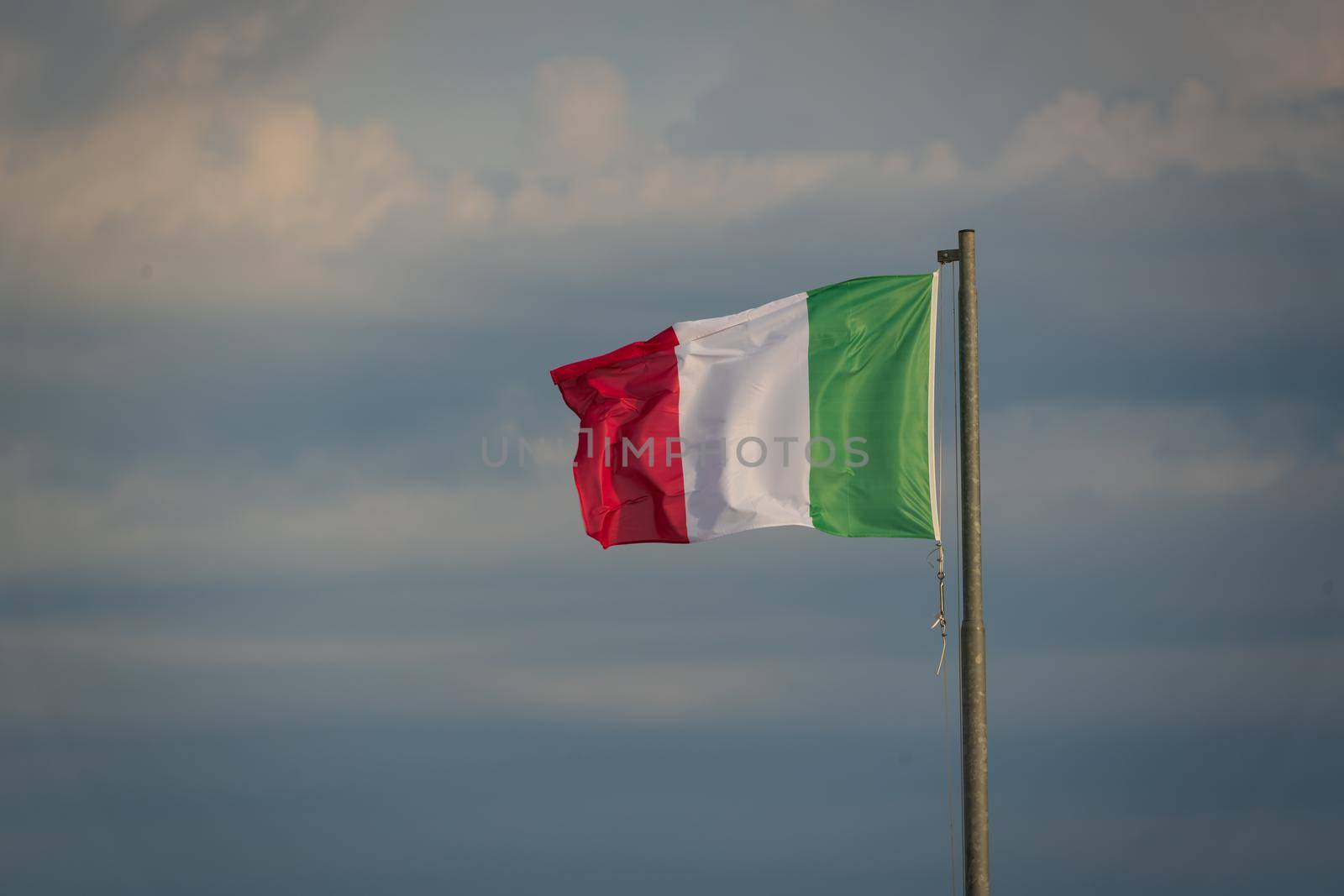 Large Italian flag waving in the wind at sunrise