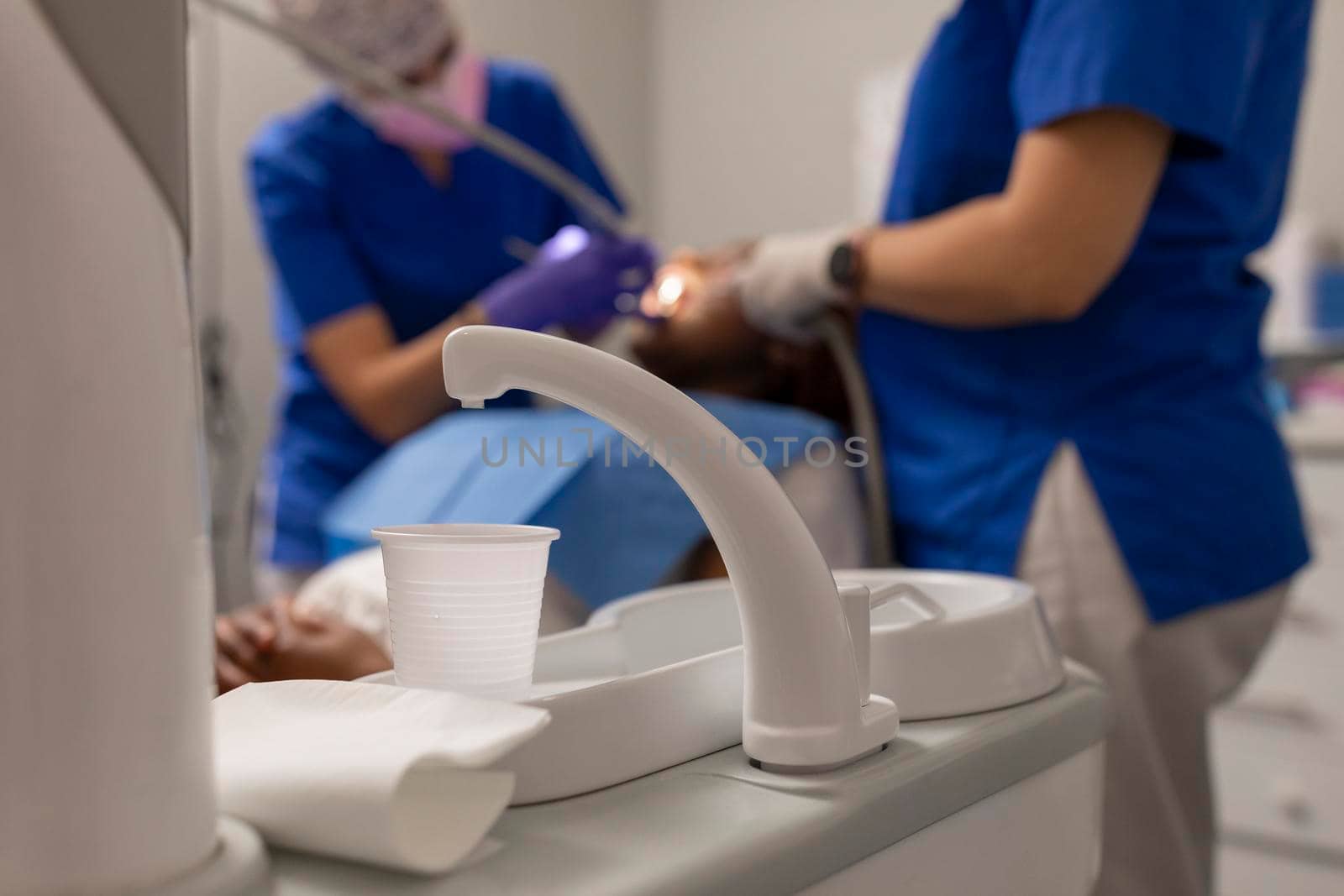 A close up view of a faucet, plastic cup and basin at the dental clinic