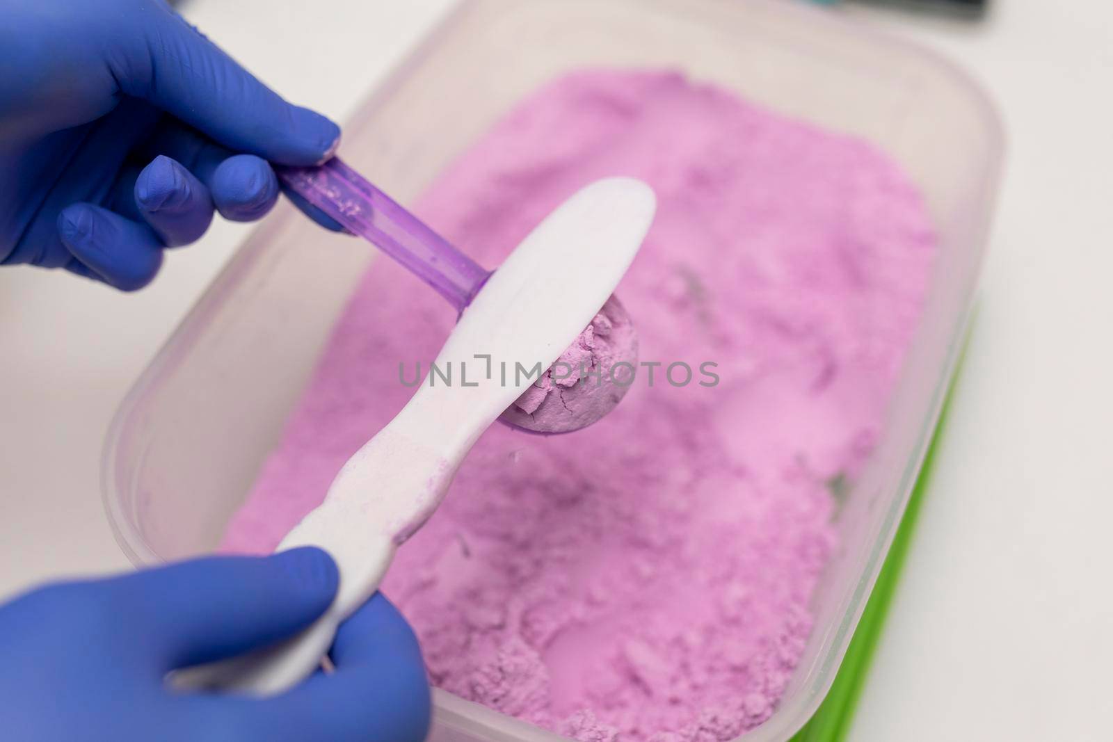 Close up view of the hands of a dentist woman mixing some plaster for her client at the dental clinic