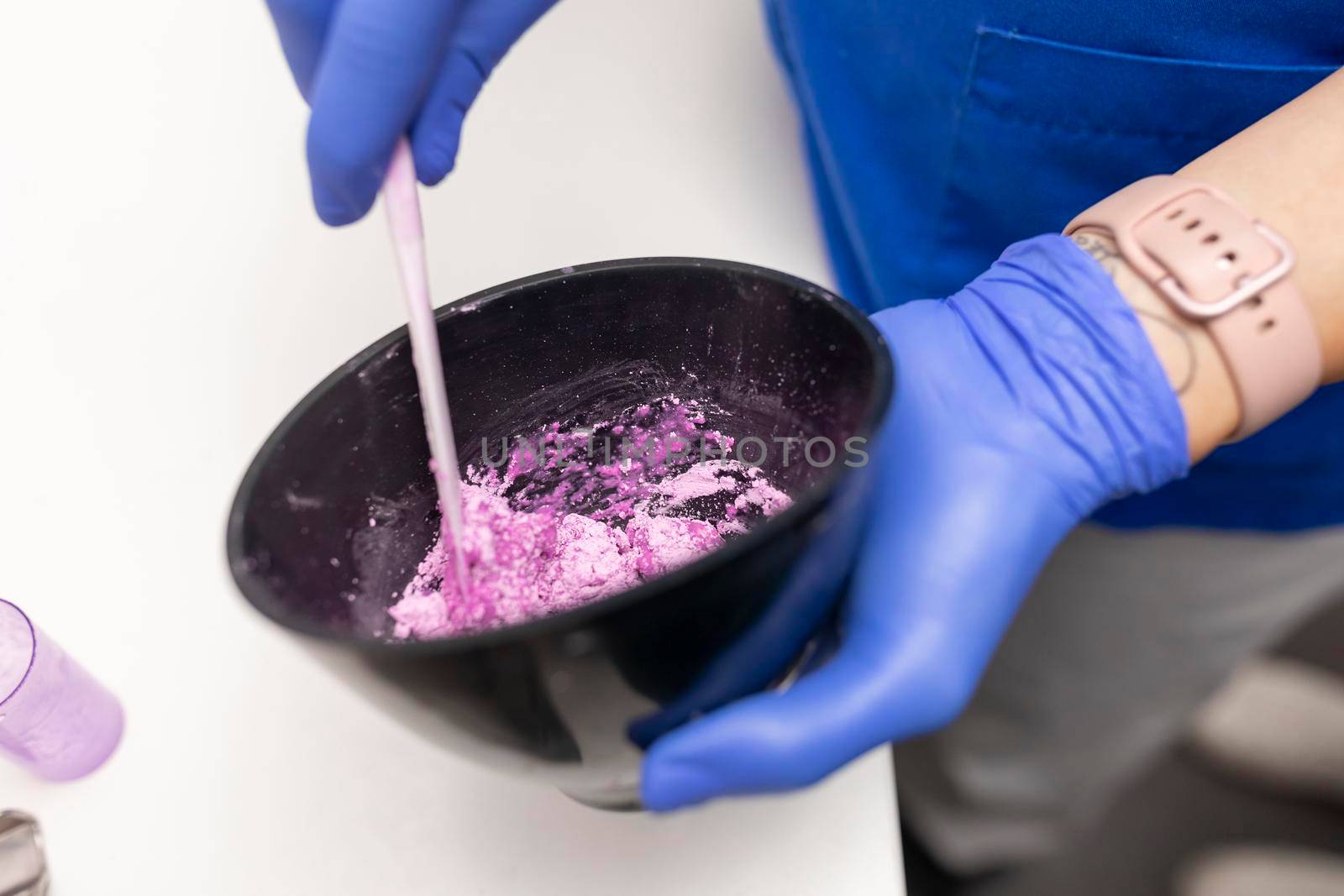 Close up view of the hands of a dentist woman mixing some plaster for her client by stockrojoverdeyazul