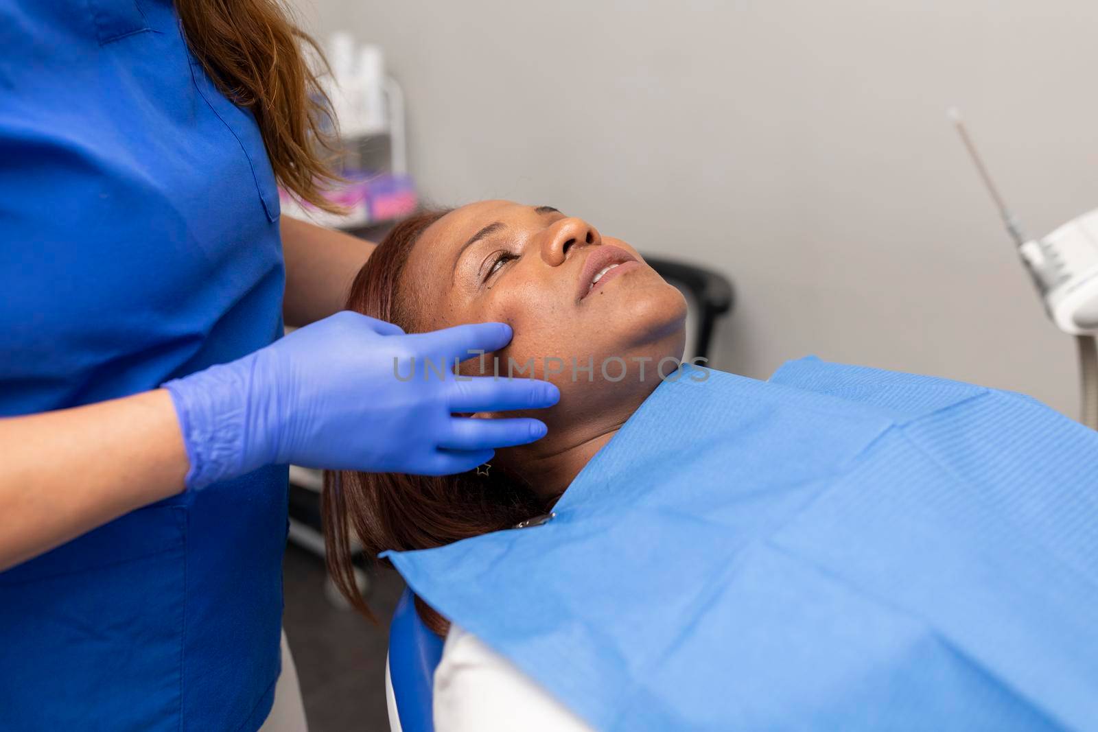 A black woman patient laying on the dental chair prior to be treated by stockrojoverdeyazul