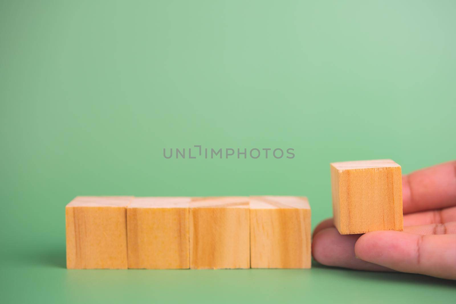 hand holding cube wood block blank on green background. copy space by aoo3771