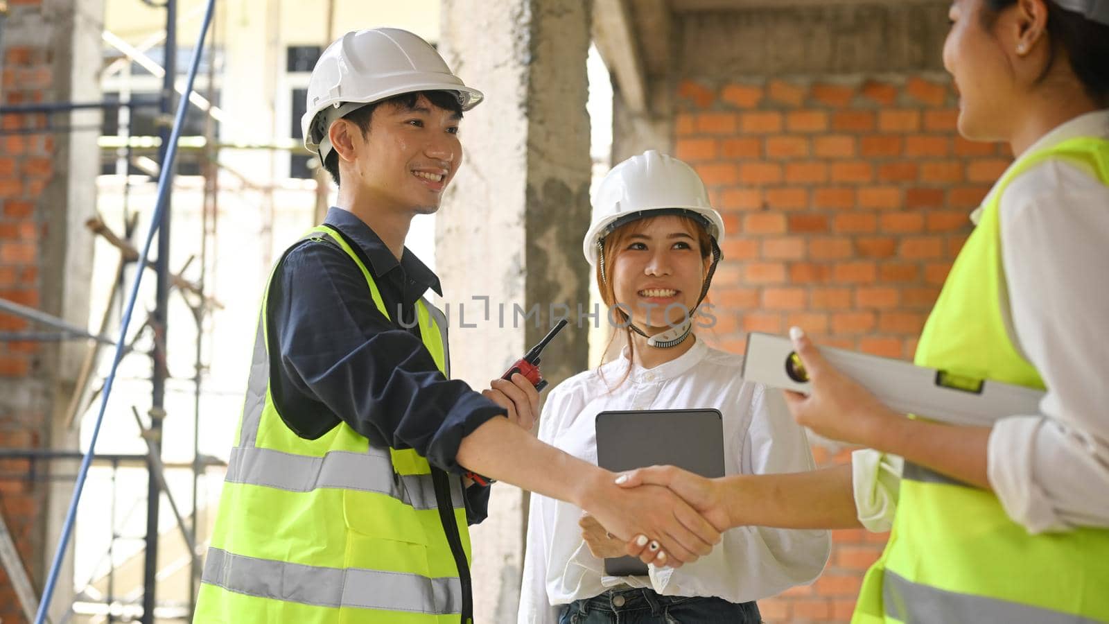 Smiling civil engineer and investor shaking hands for architectural project, agreement success in working site.