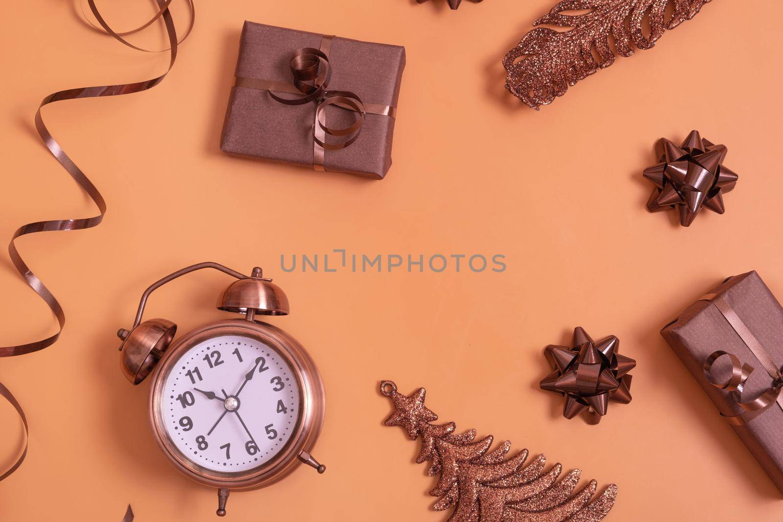 Flat lay alarm clock and gift boxes, Christmas tree on colored background top view with copy space.