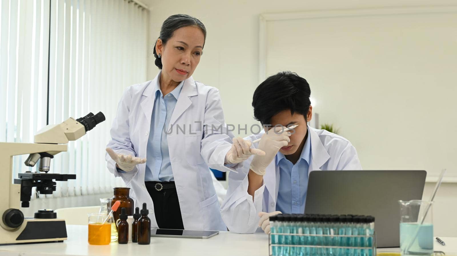 Stressed asian male scientist feeling tired, upset or having problems results of the experiment.