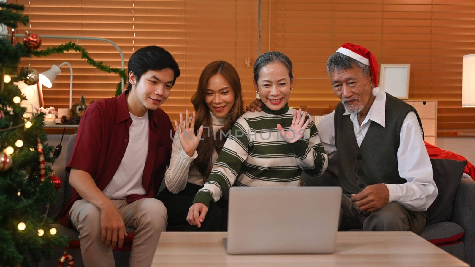 Happy family having a video call on laptop, congratulating relatives during Christmas or New year holidays by prathanchorruangsak