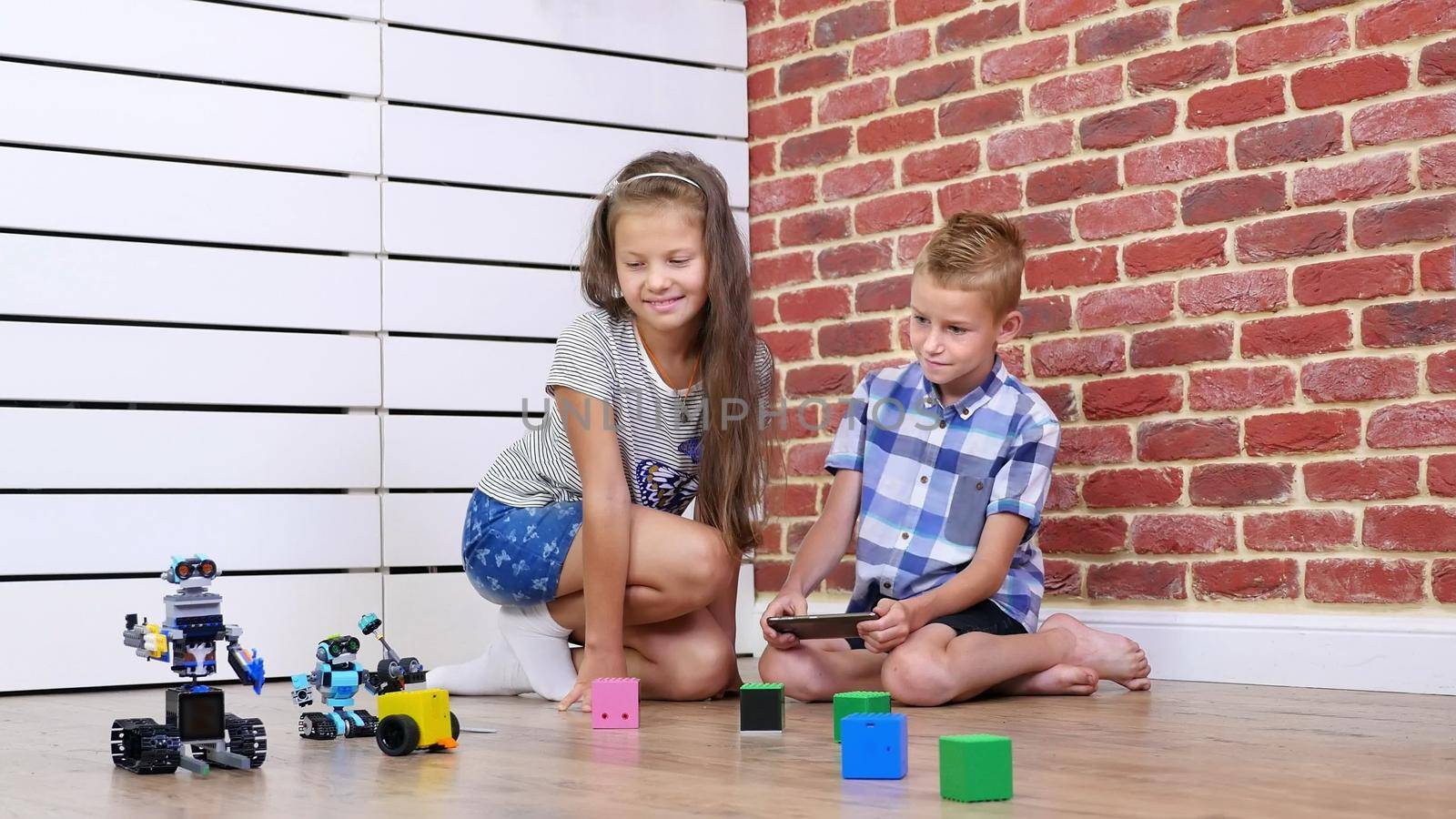 seven-year-old boy and girl play electronic robots, cars, modern toys on the radio control. new technologies in the children's gaming industry. little geniuses. High quality photo