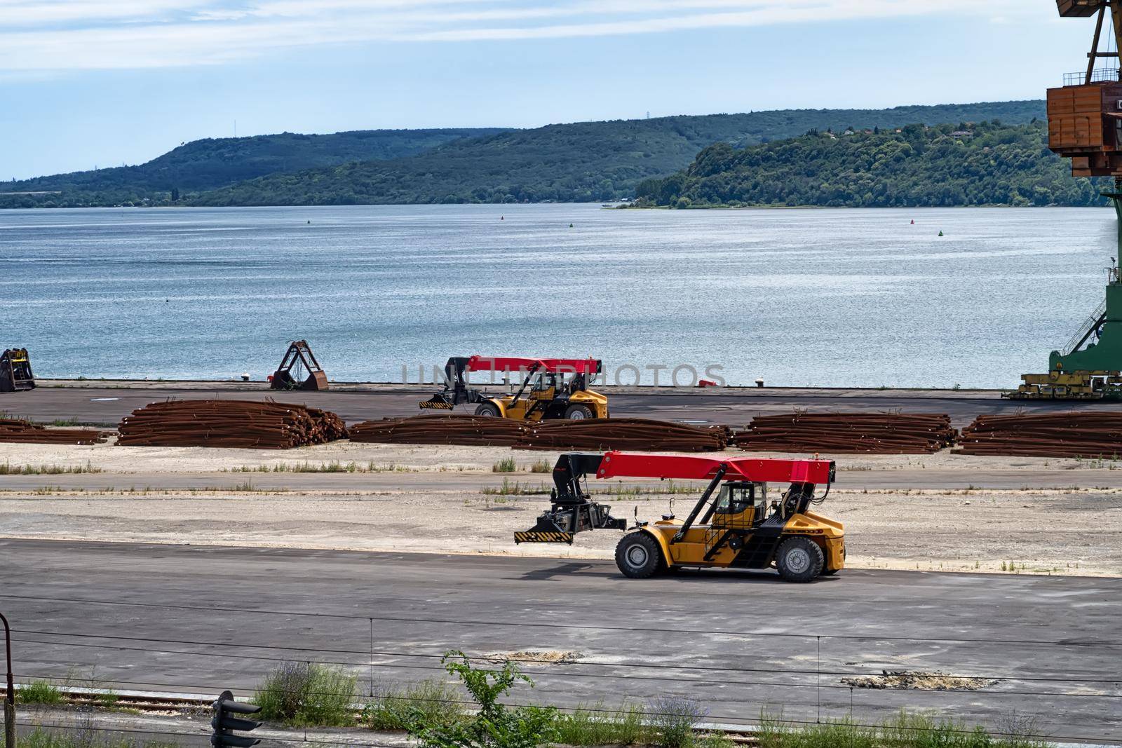 Telescopic handlers working on a shipping warehouse. Day view. Work in port.	