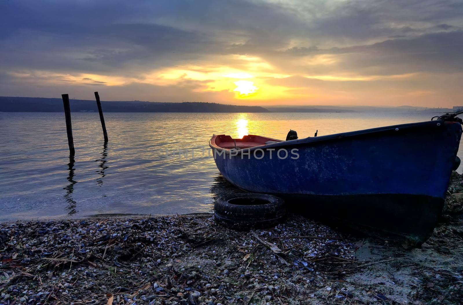 beauty sunset with the lonely blue boat on the  beach 