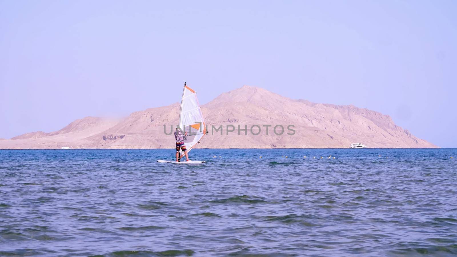 man learns to ride on a board with a sail, windsurfing. windsurfing on the crystal clear water. High quality photo