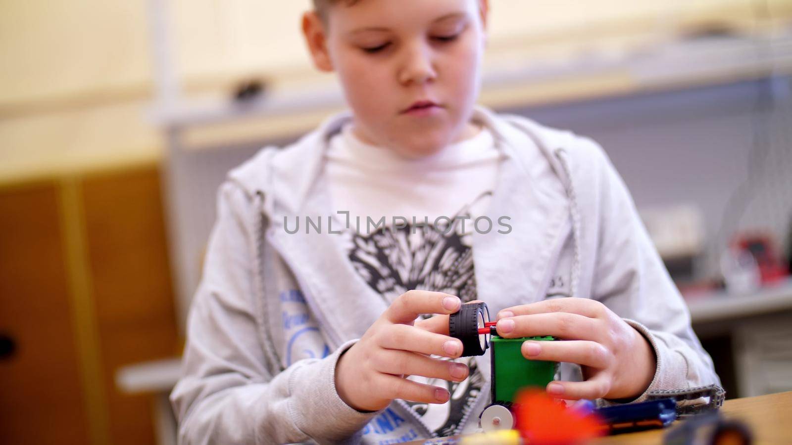 the boy of 11 years, plays in the designer from cubes, plates, circuits, wires. a small inventor creates robots, machines from different parts of the designer. High quality photo