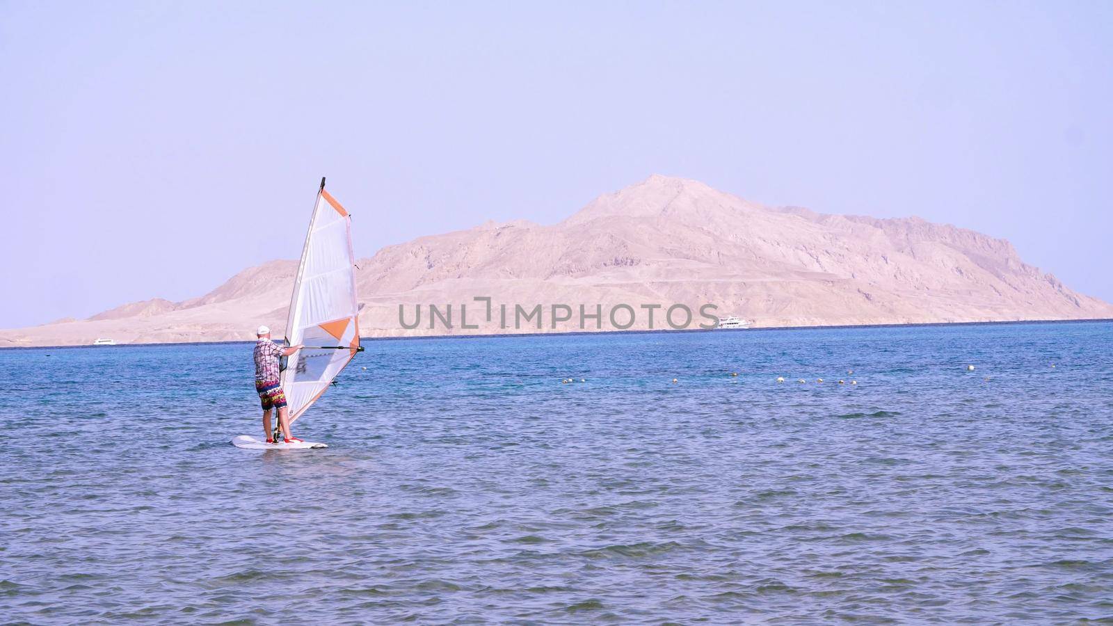 man learns to ride on a board with a sail, windsurfing. windsurfing on the crystal clear water. High quality photo