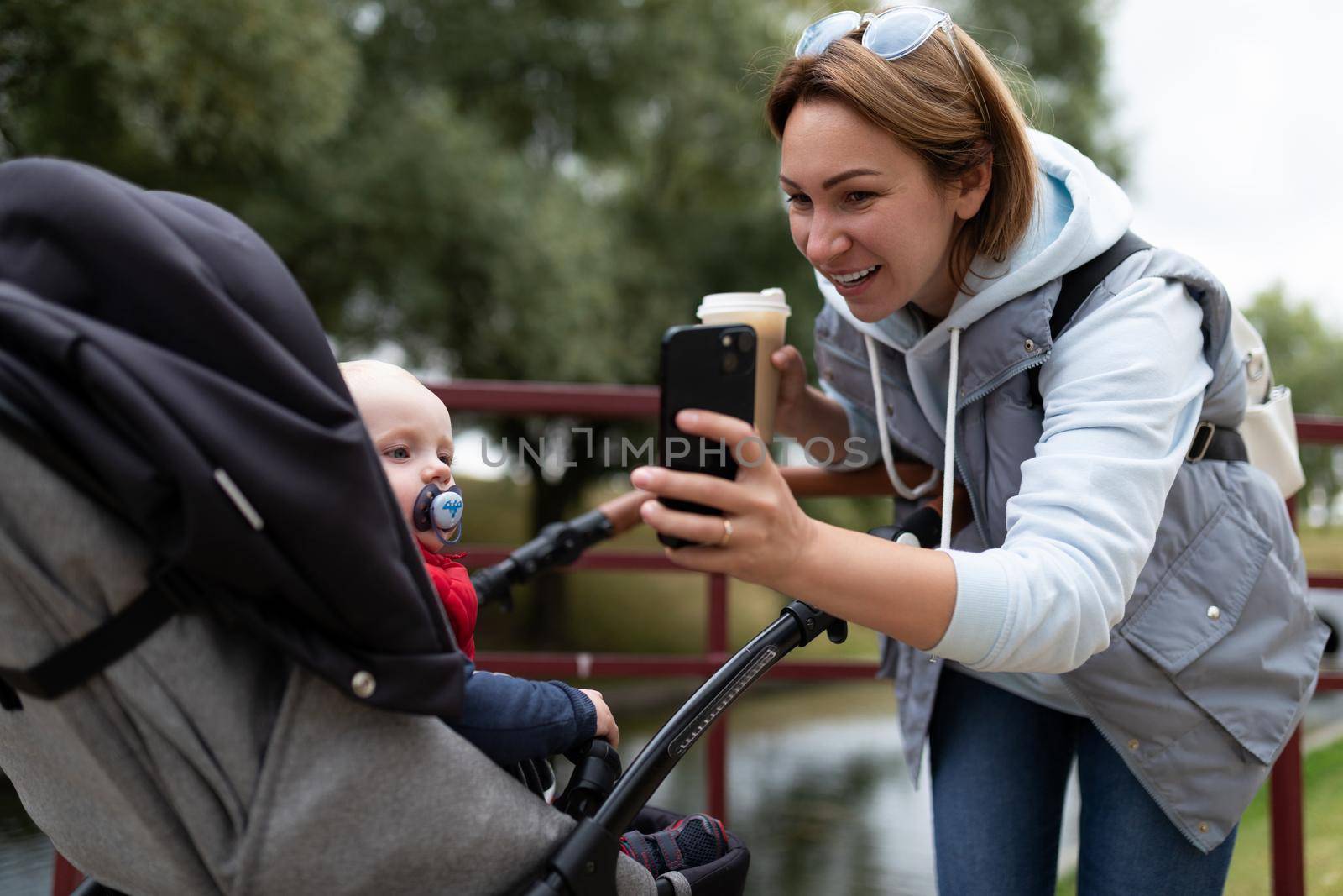 young mother shows a child in a stroller cartoon on the phone.