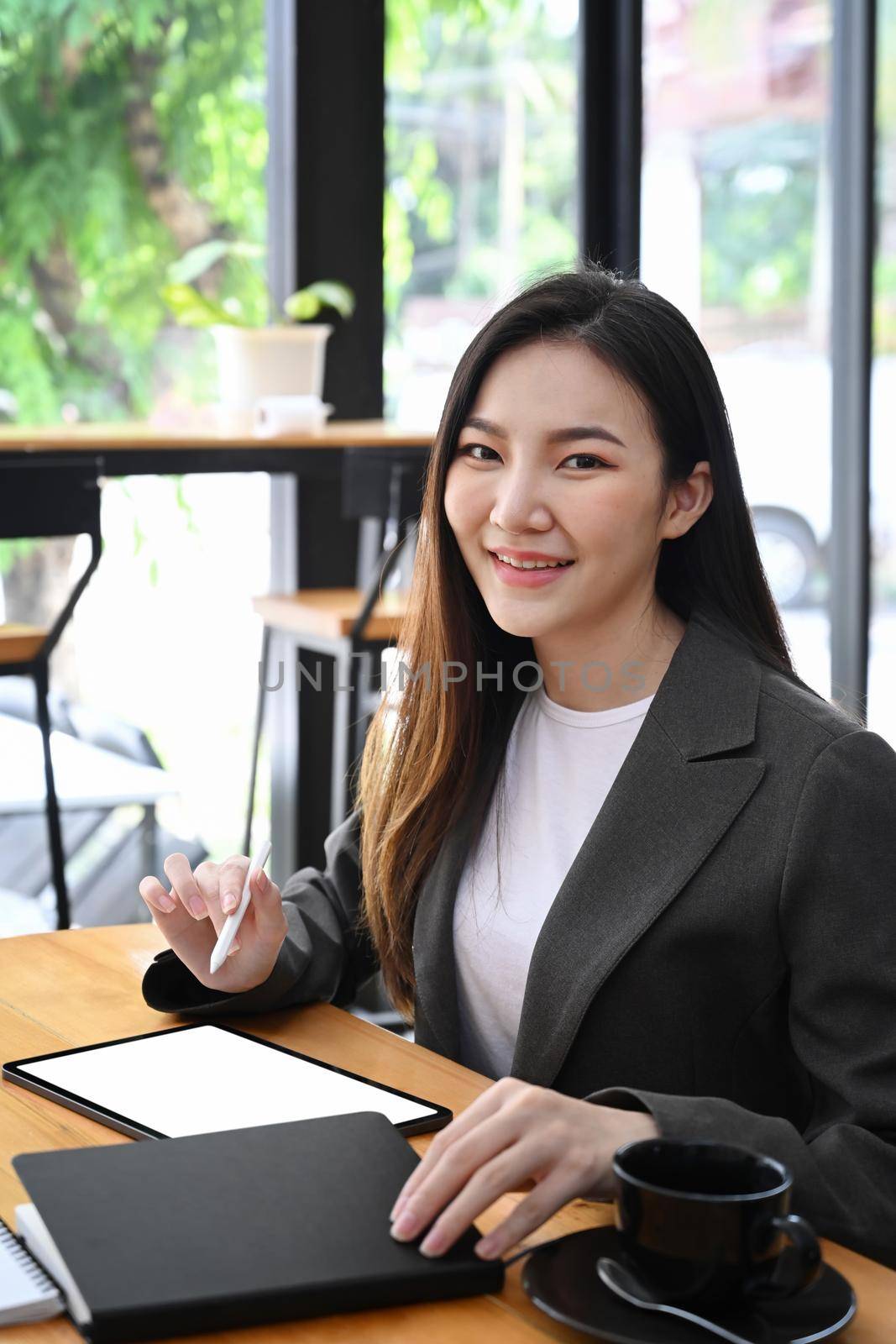 Attractive businesswoman sitting in office and smiling to camera. by prathanchorruangsak