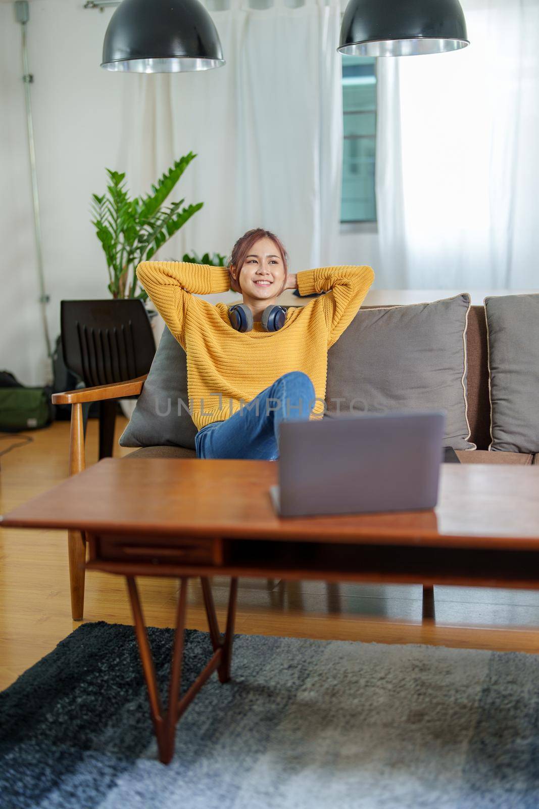 Portrait of a young Asian woman using a computer on the sofa.