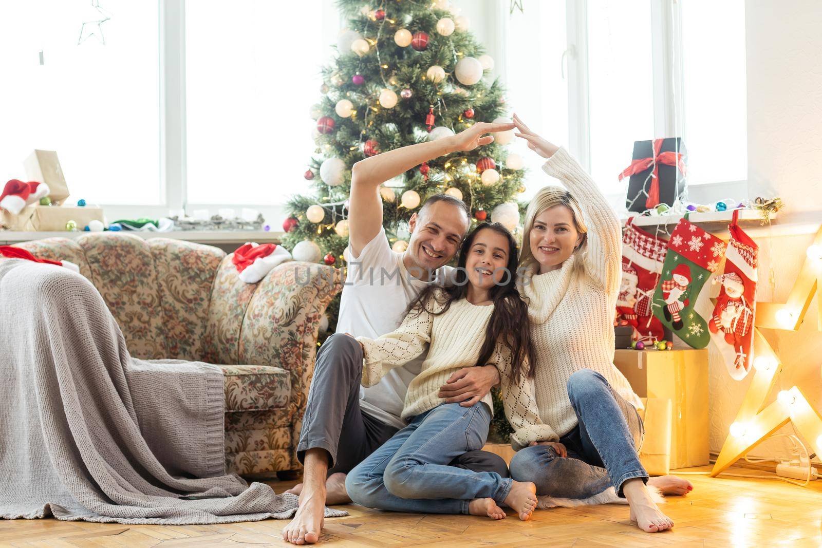 Beautiful young family enjoying their holiday time together, decorating Christmas tree, arranging the christmas lights and having fun