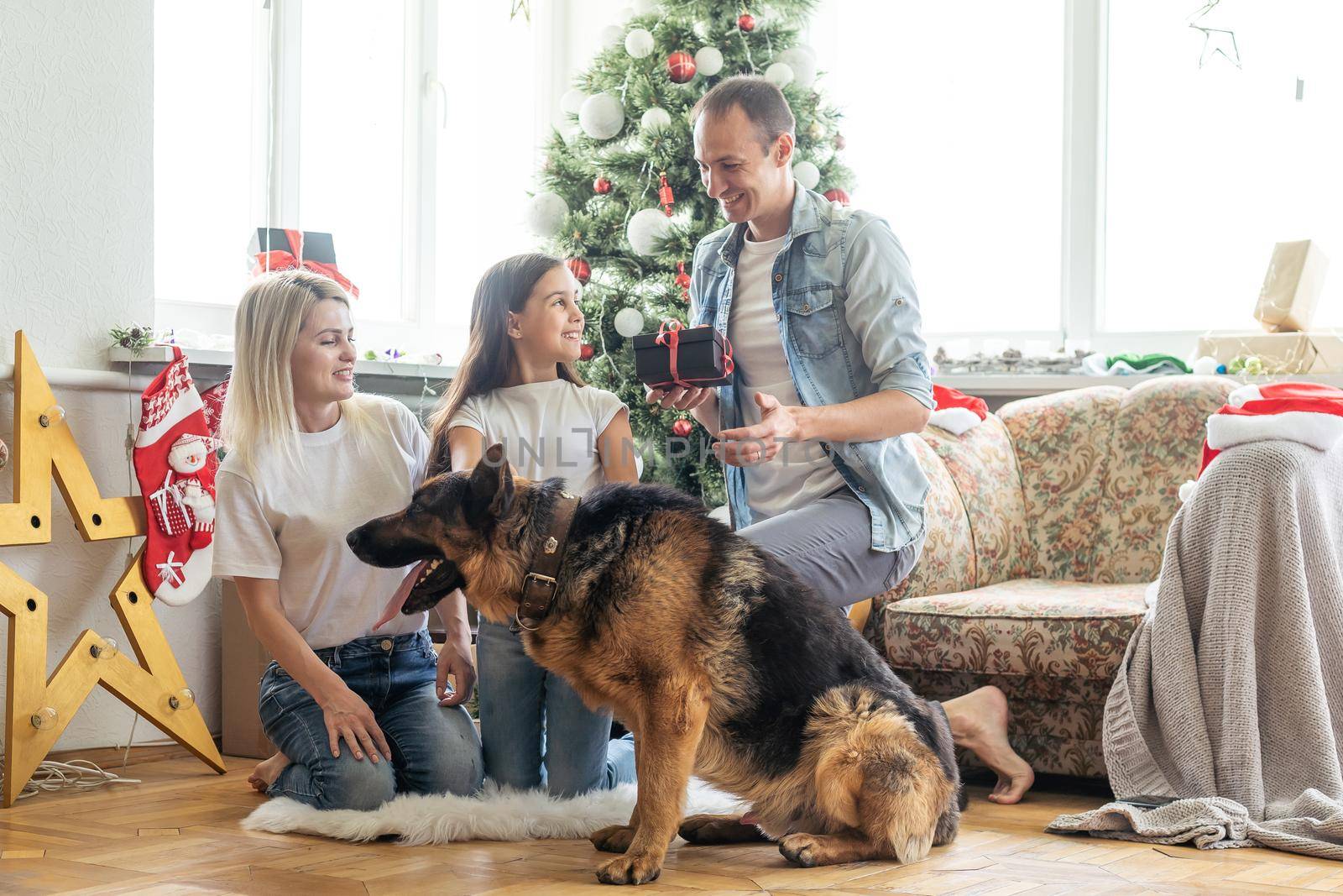 happy family and cute dog having fun at christmas tree. atmospheric emotional moments. merry christmas and happy new year concept