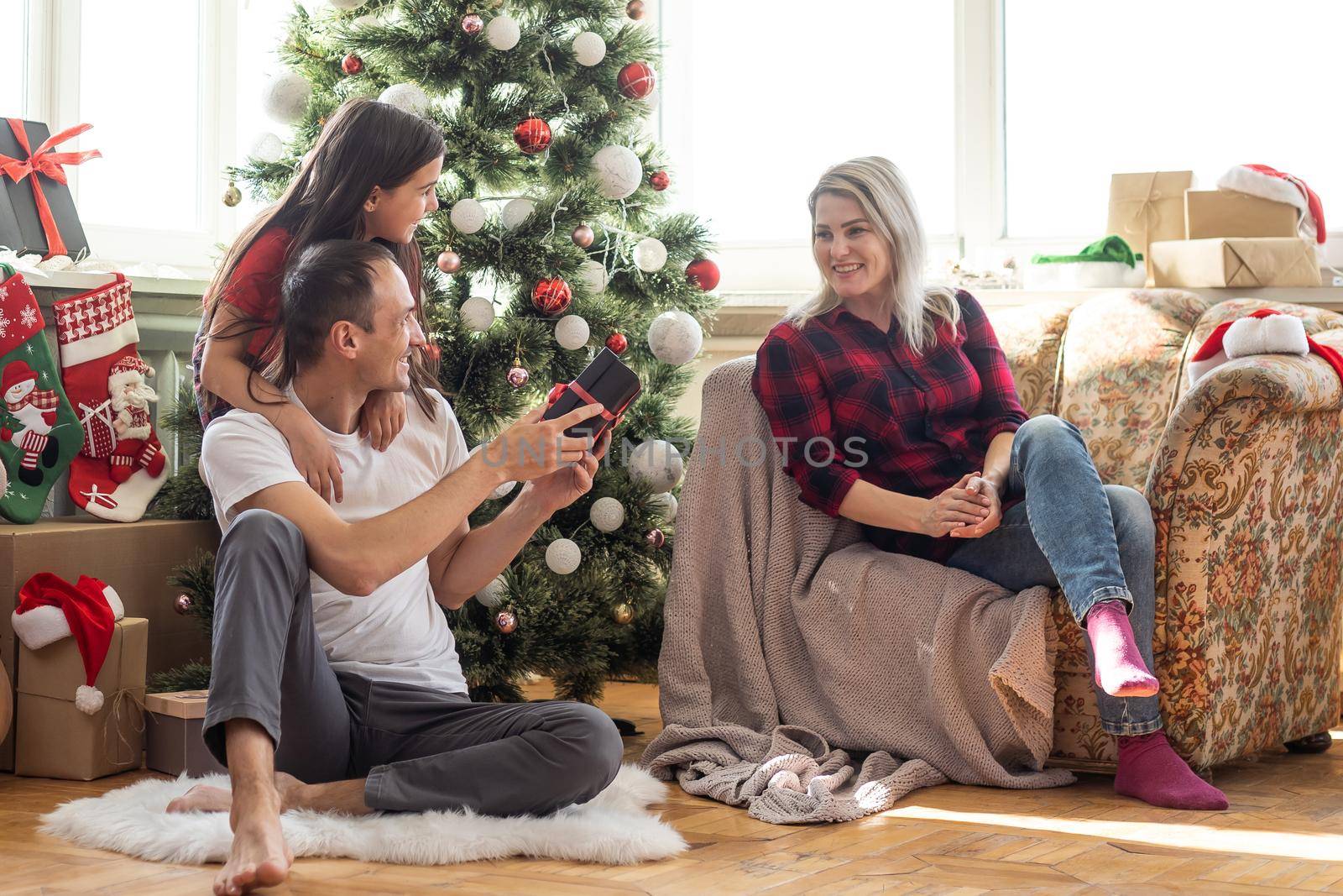 Young happy family while celebrating Christmas at home. by Andelov13