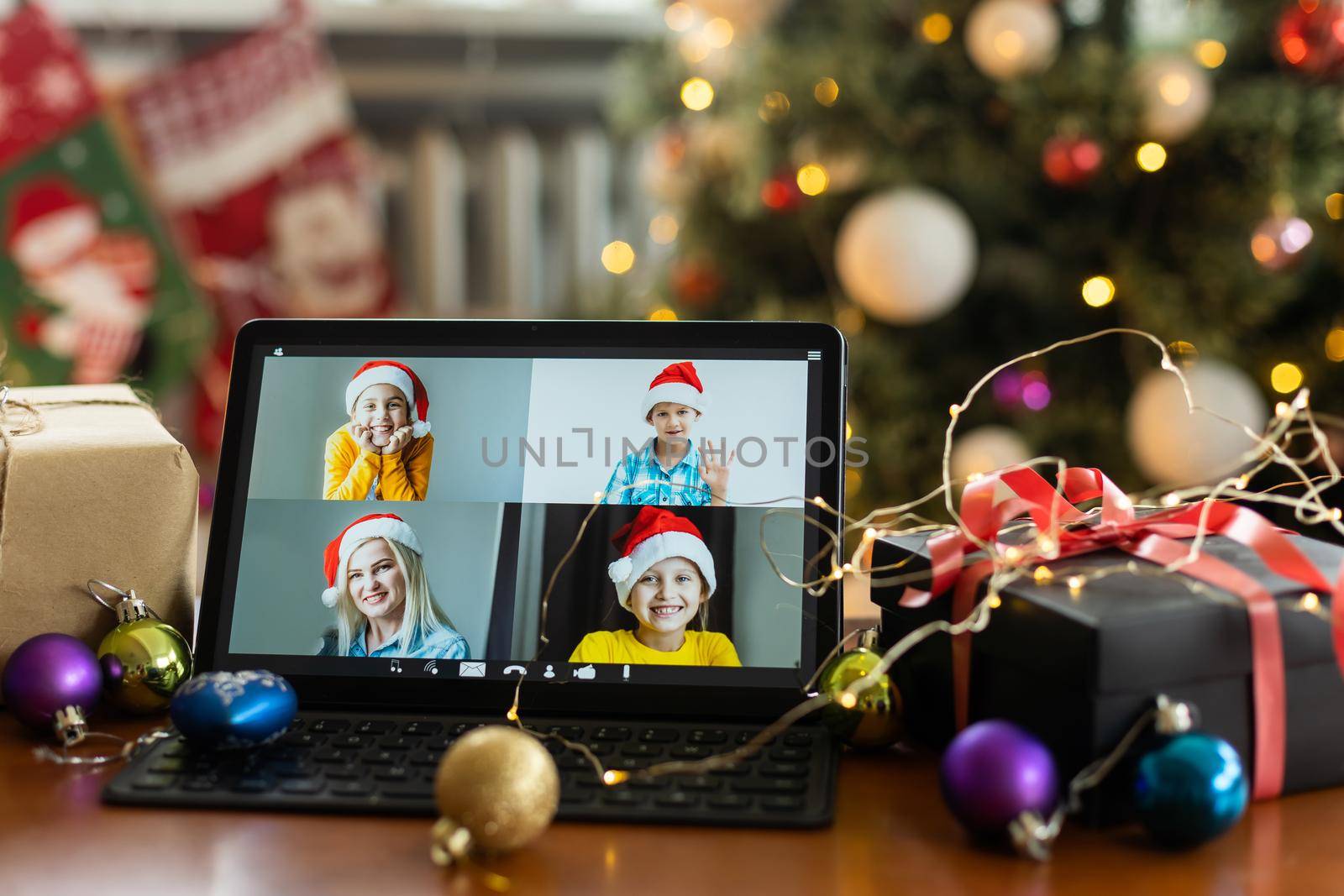 Family video call with kid presenting gift by remote chat digital tablet screen on Merry Christmas table holiday background. Xmas online virtual family party celebration, Happy New Year videocall.