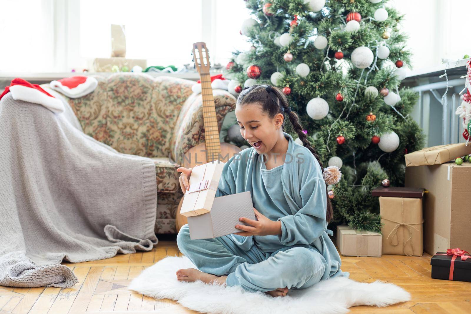 Merry Christmas and Happy Holidays Cute little child girl is decorating the Christmas tree indoors