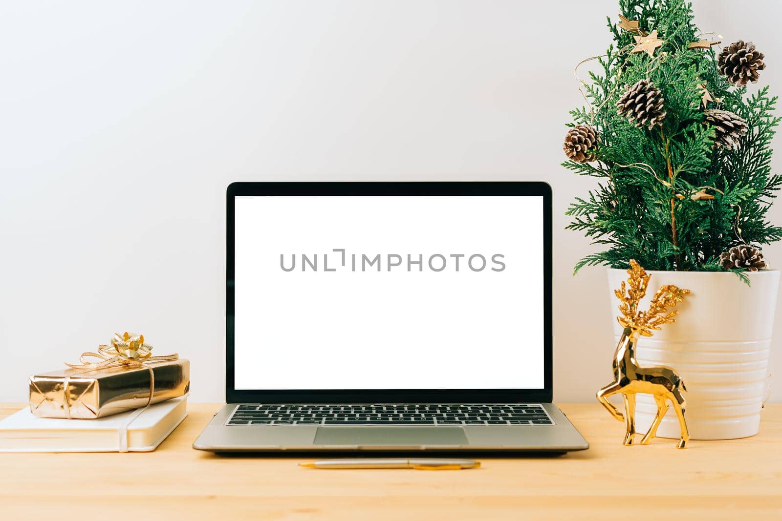 Laptop with mockup blank screen on wooden table with Christmas gift, fir tree on white background. Computer with Mock up and copy space for text.