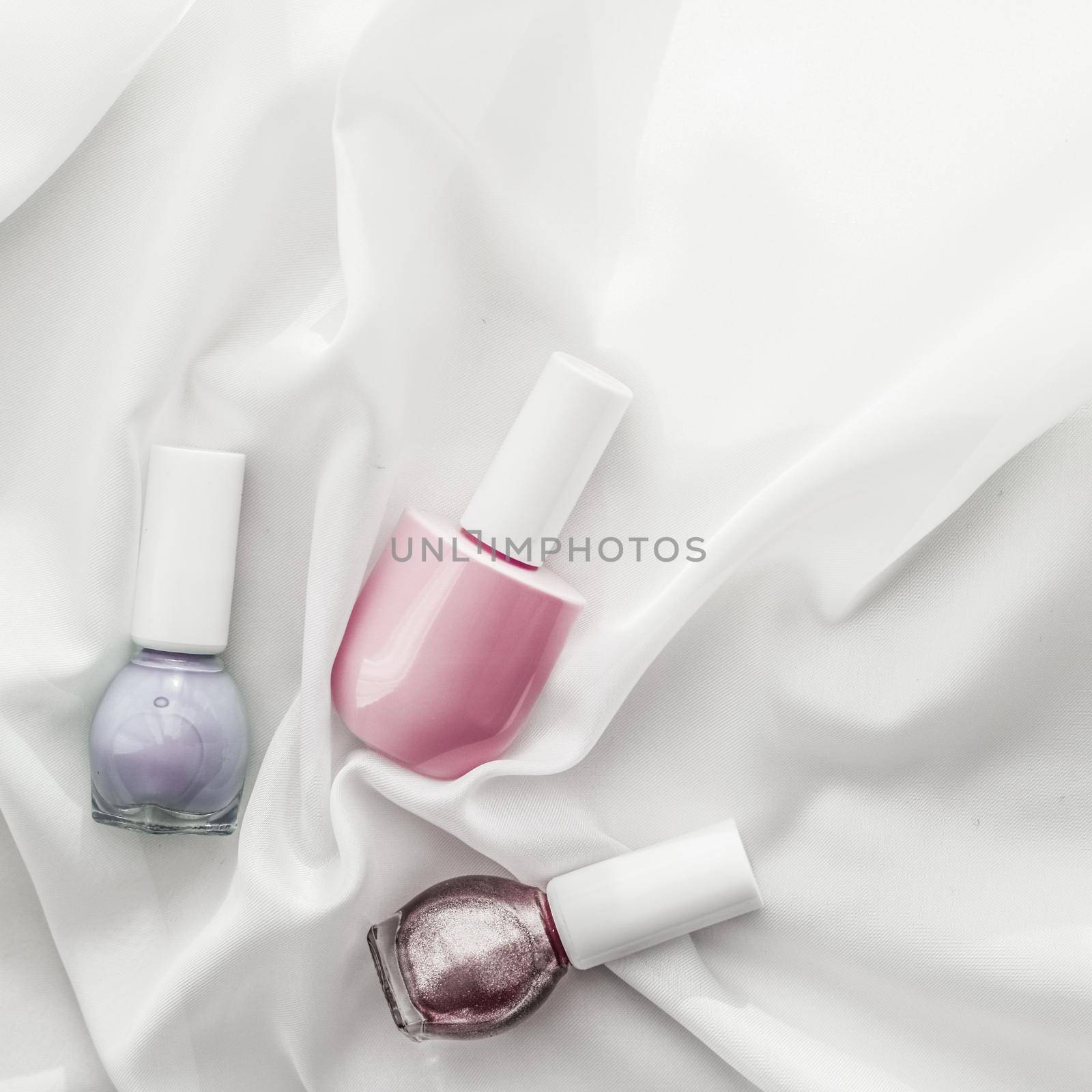 Nail polish bottles on silk background, french manicure products and nailpolish make-up cosmetics for luxury beauty brand and holiday flatlay art design by Anneleven