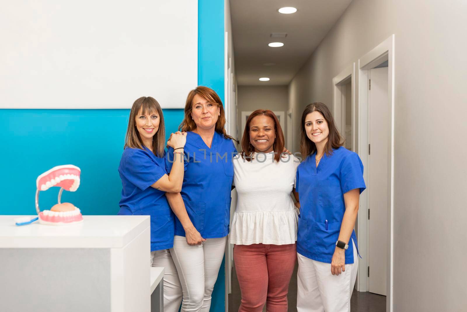 A group of female dentists at the dental clinic, smiling with a satisfied client by stockrojoverdeyazul