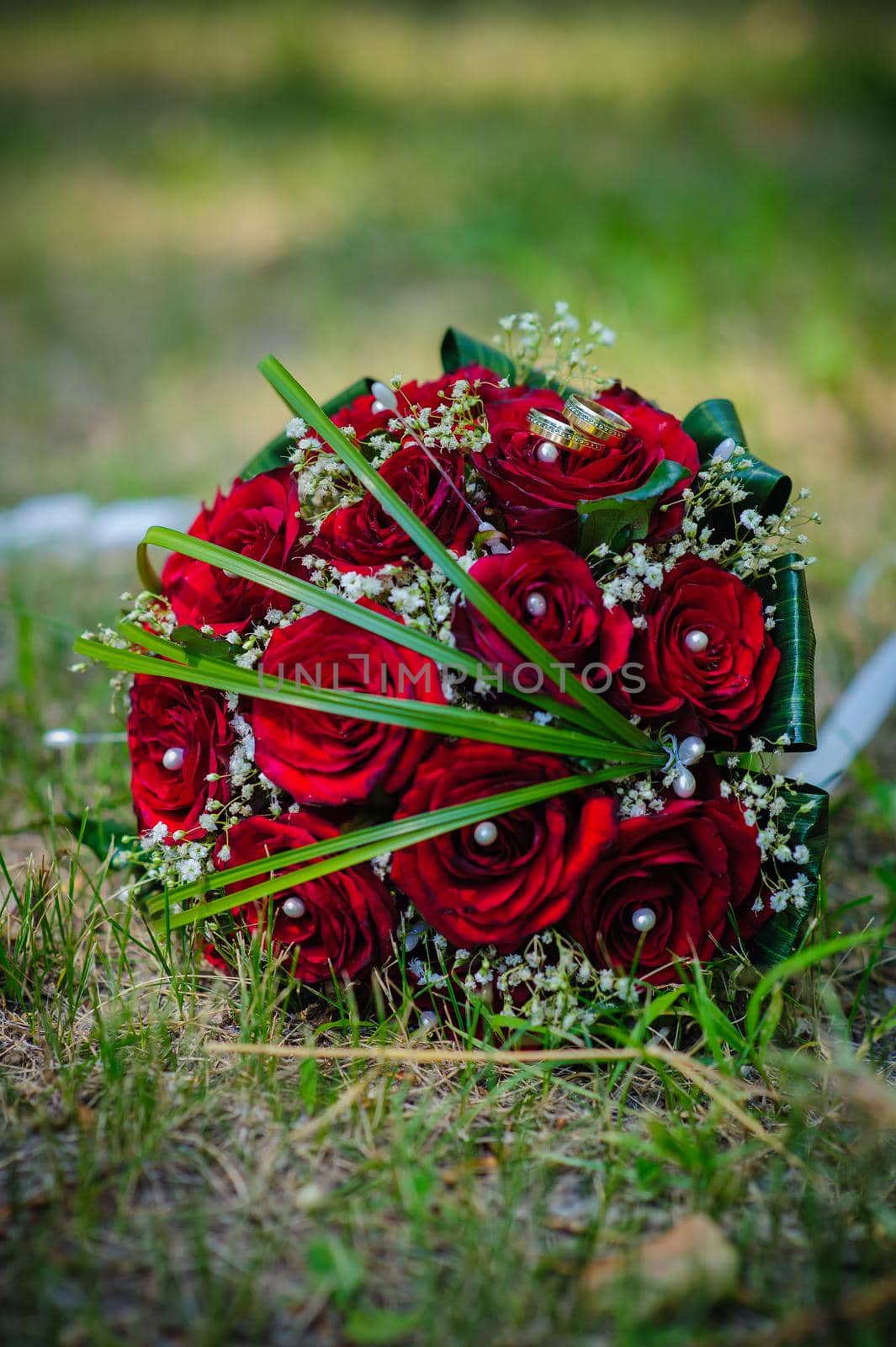 Bridal wedding bouquet of flowers. Wedding bouquet of red roses lying on a grass by Andrii_Ko