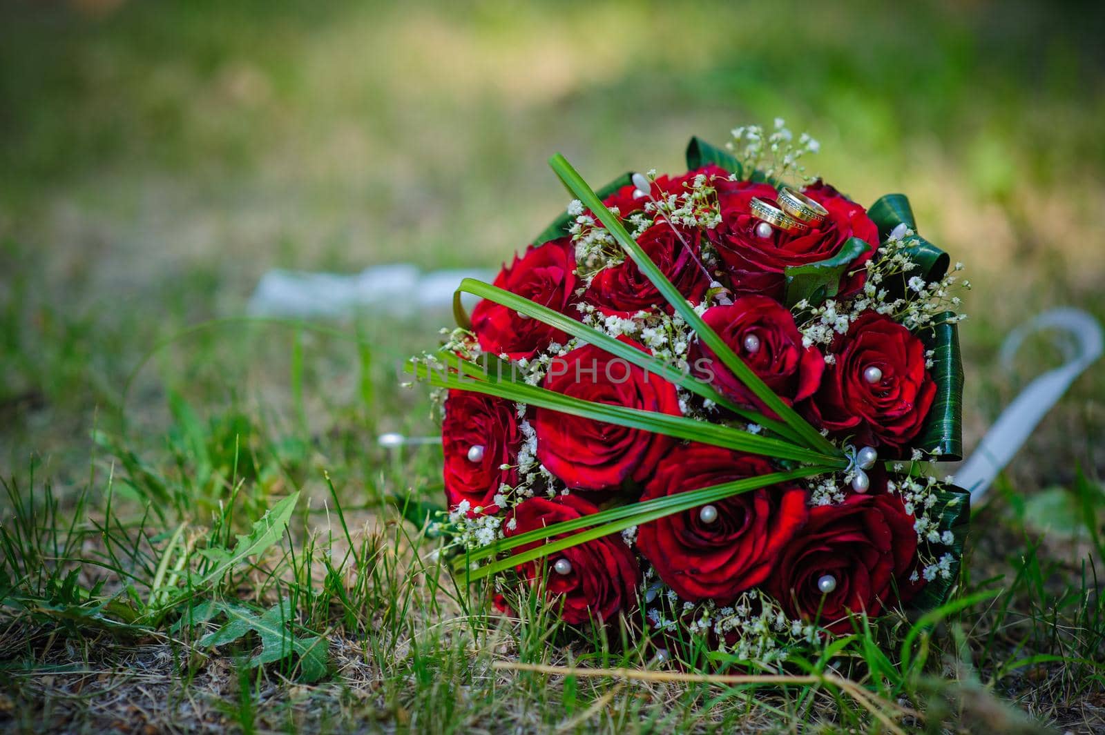 Bridal wedding bouquet of flowers. Wedding bouquet of red roses lying on a grass.