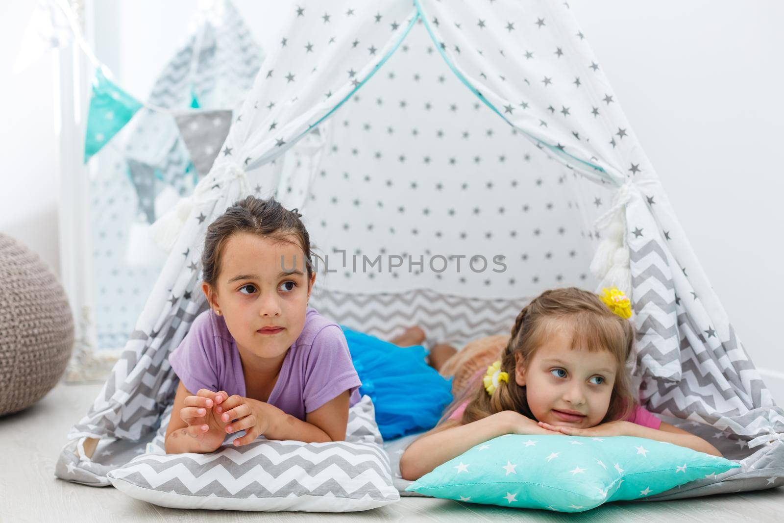 childhood and hygge concept - happy little girls playing in kids tent.